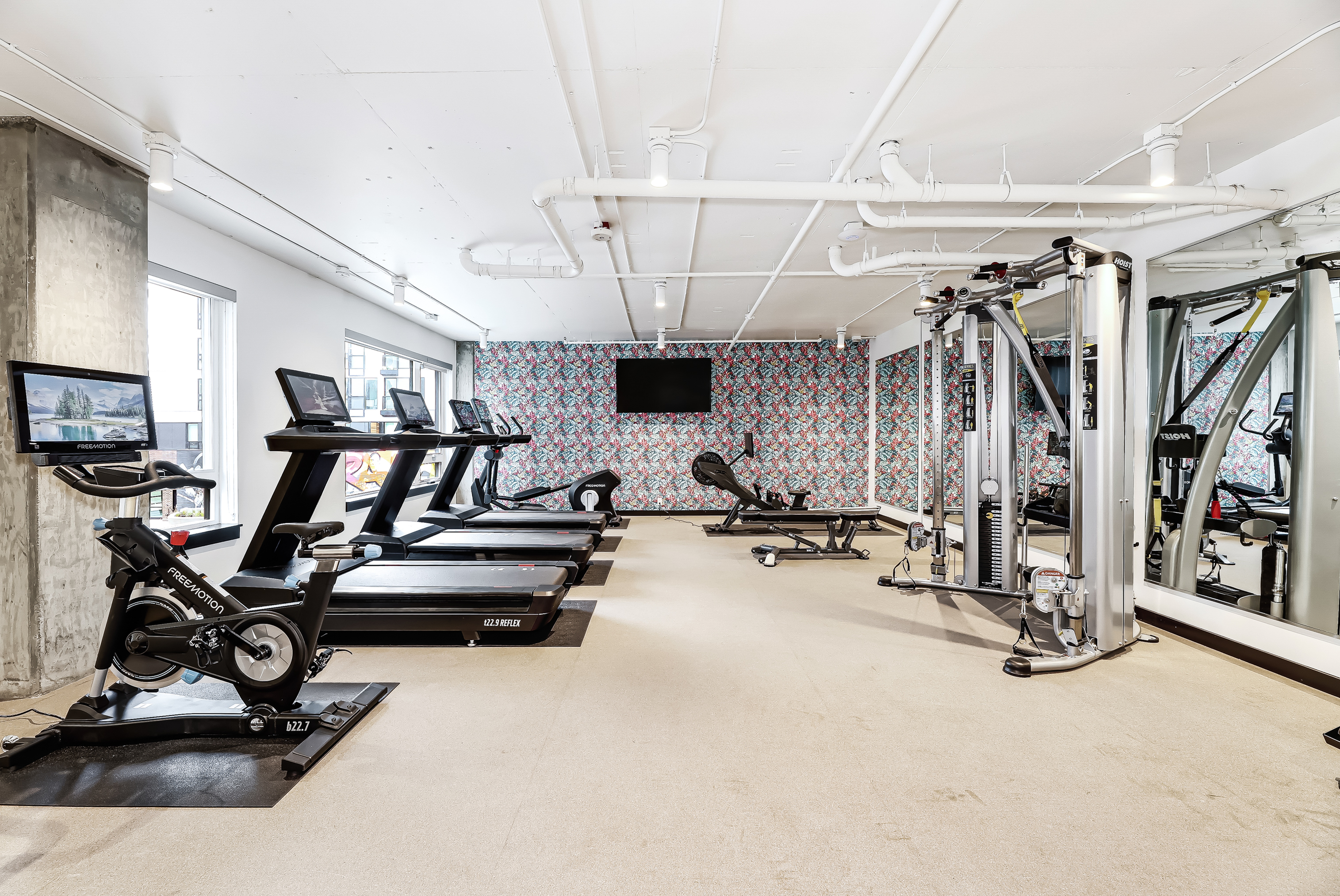 Modern fitness center with state-of-the-art equipment, including treadmills, exercise bikes, and strength training machines, in a stylish, well-lit environment.