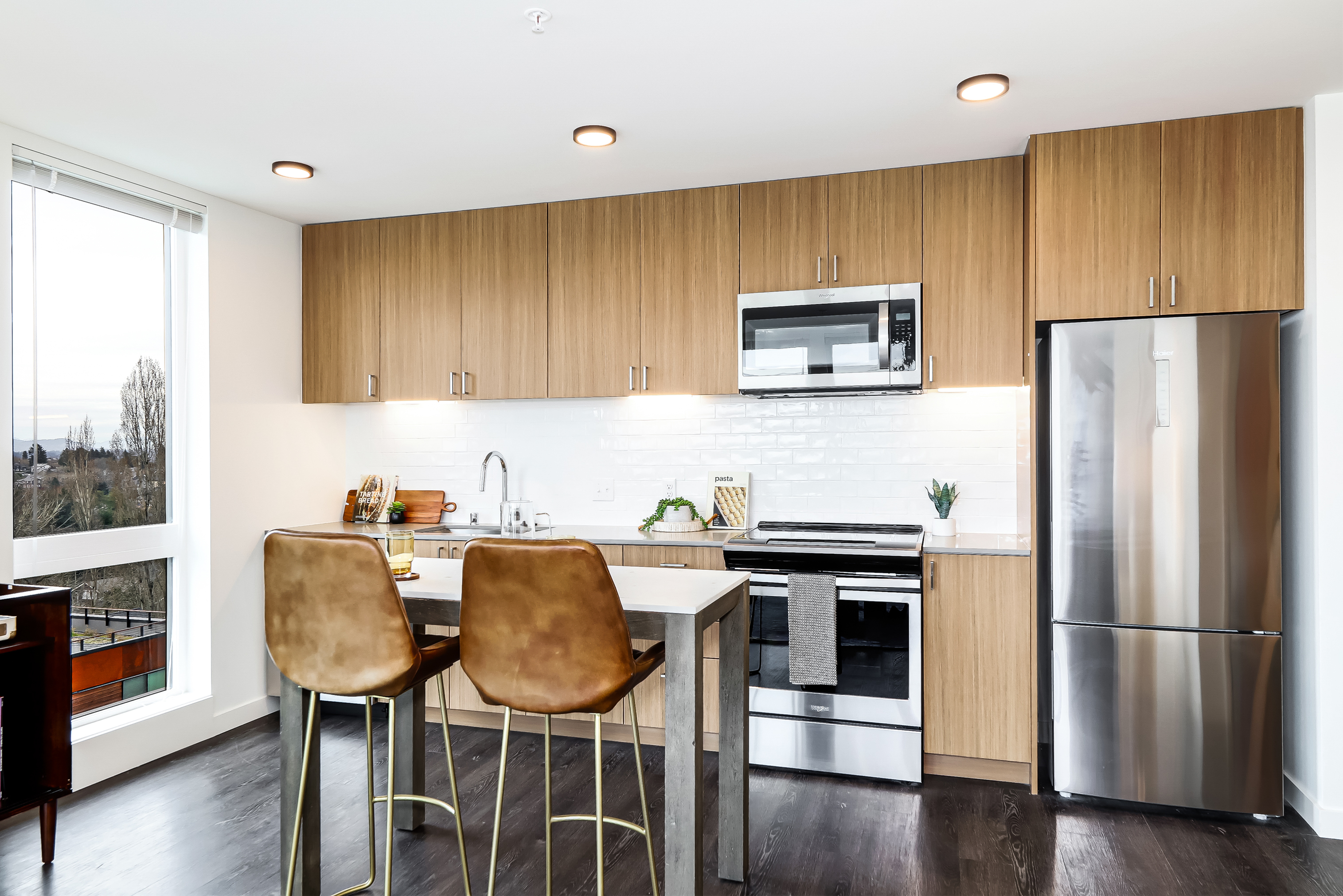 Modern kitchen design with sleek wood cabinets, stainless steel appliances, and a chic breakfast bar with stylish seating.