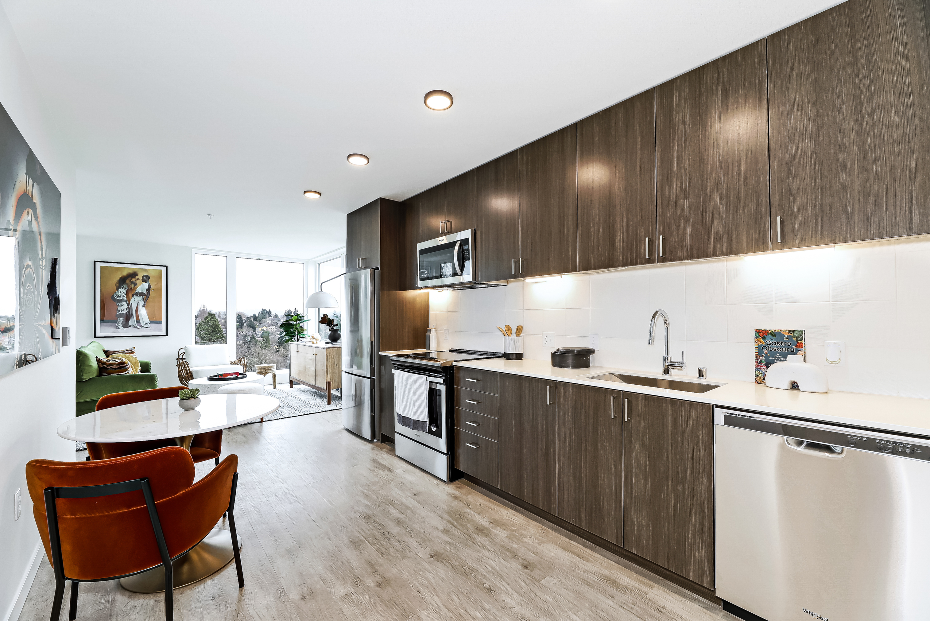 Contemporary apartment kitchen with sleek dark cabinetry, stainless steel appliances, and inviting open layout featuring stylish dining area and scenic views.
