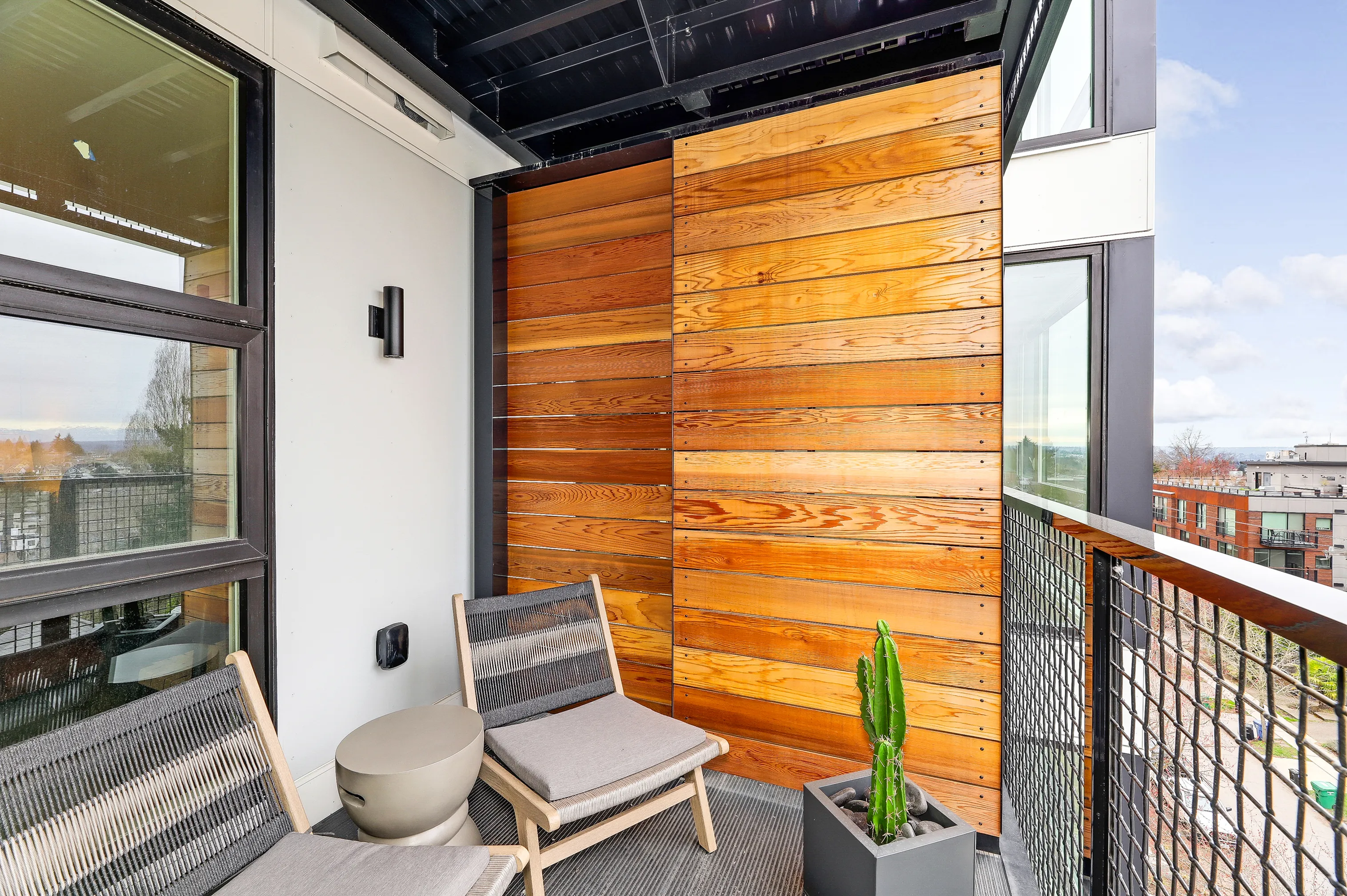 Chic urban balcony with sleek wooden paneling, comfortable seating, and modern decor for a serene retreat.