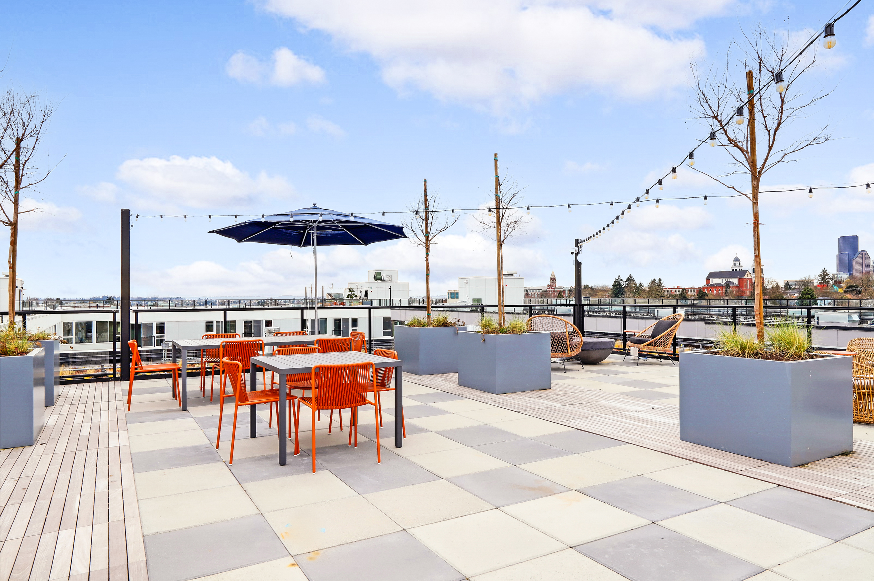Chic rooftop terrace with vibrant orange seating, stylish string lights, and scenic city views, perfect for entertaining and relaxation.
