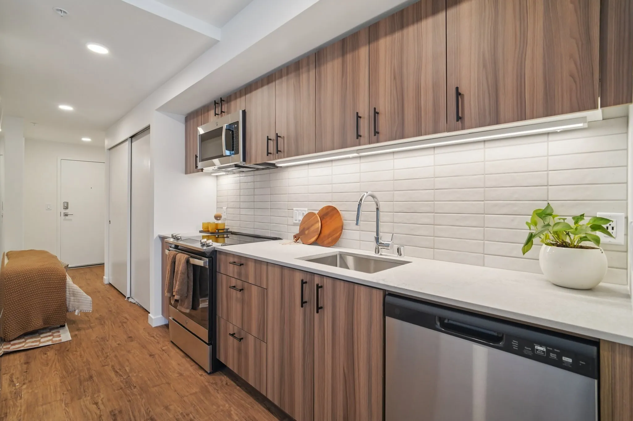Modern kitchen with sleek wooden cabinets, stainless steel appliances, and a stylish white tile backsplash, featuring a cozy dining nook.