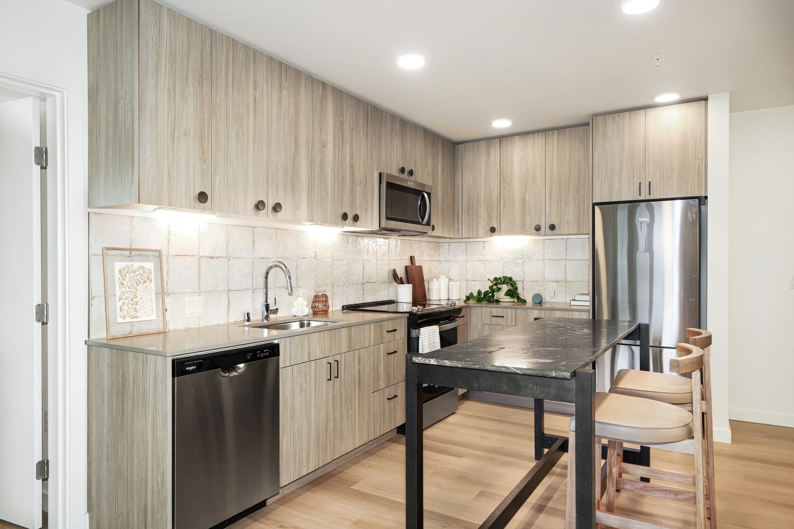 Modern kitchen with sleek wooden cabinetry, stainless steel appliances, and an elegant dark countertop island creating a stylish culinary space.