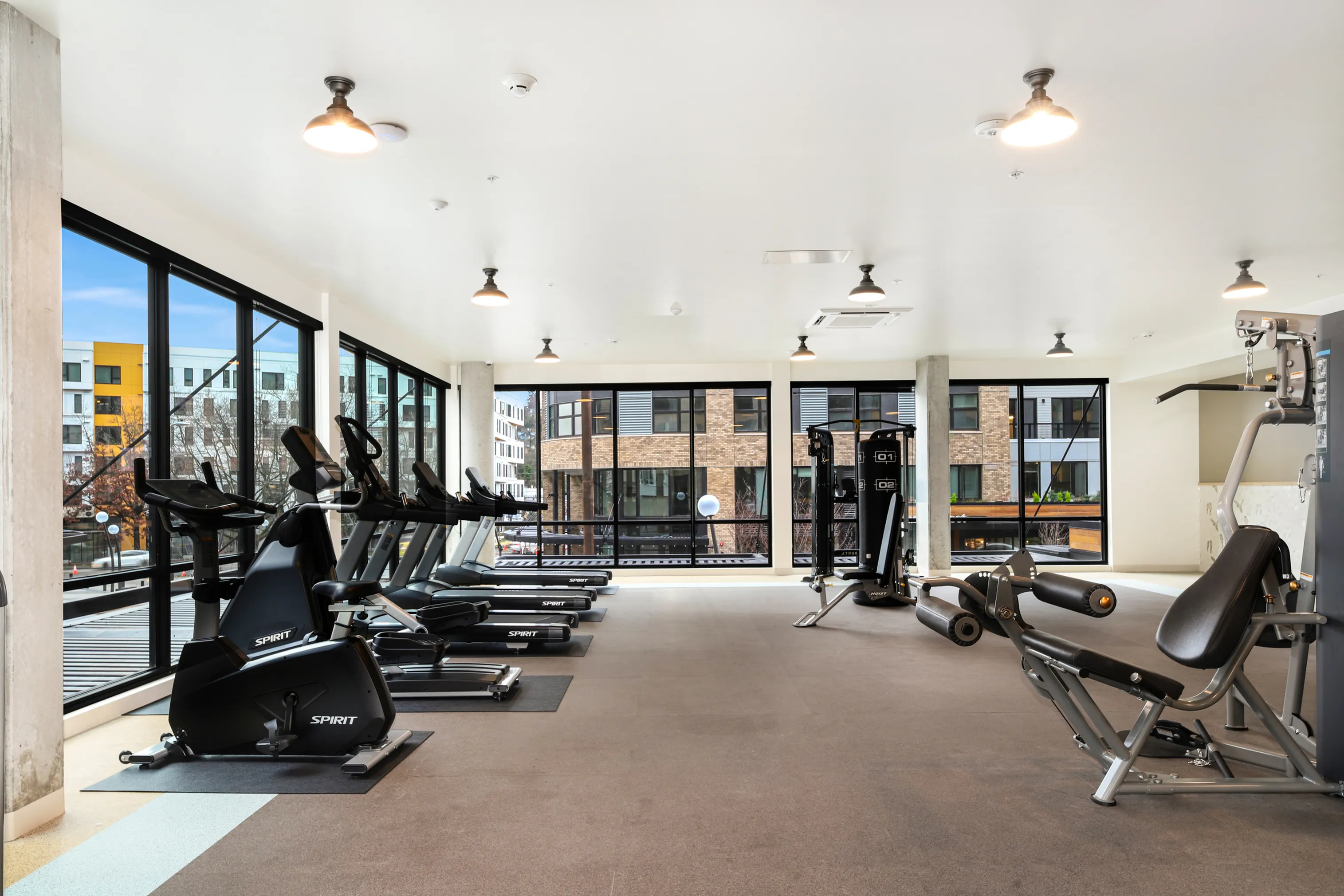 Bright and modern gym with state-of-the-art exercise equipment and large windows offering scenic city views.