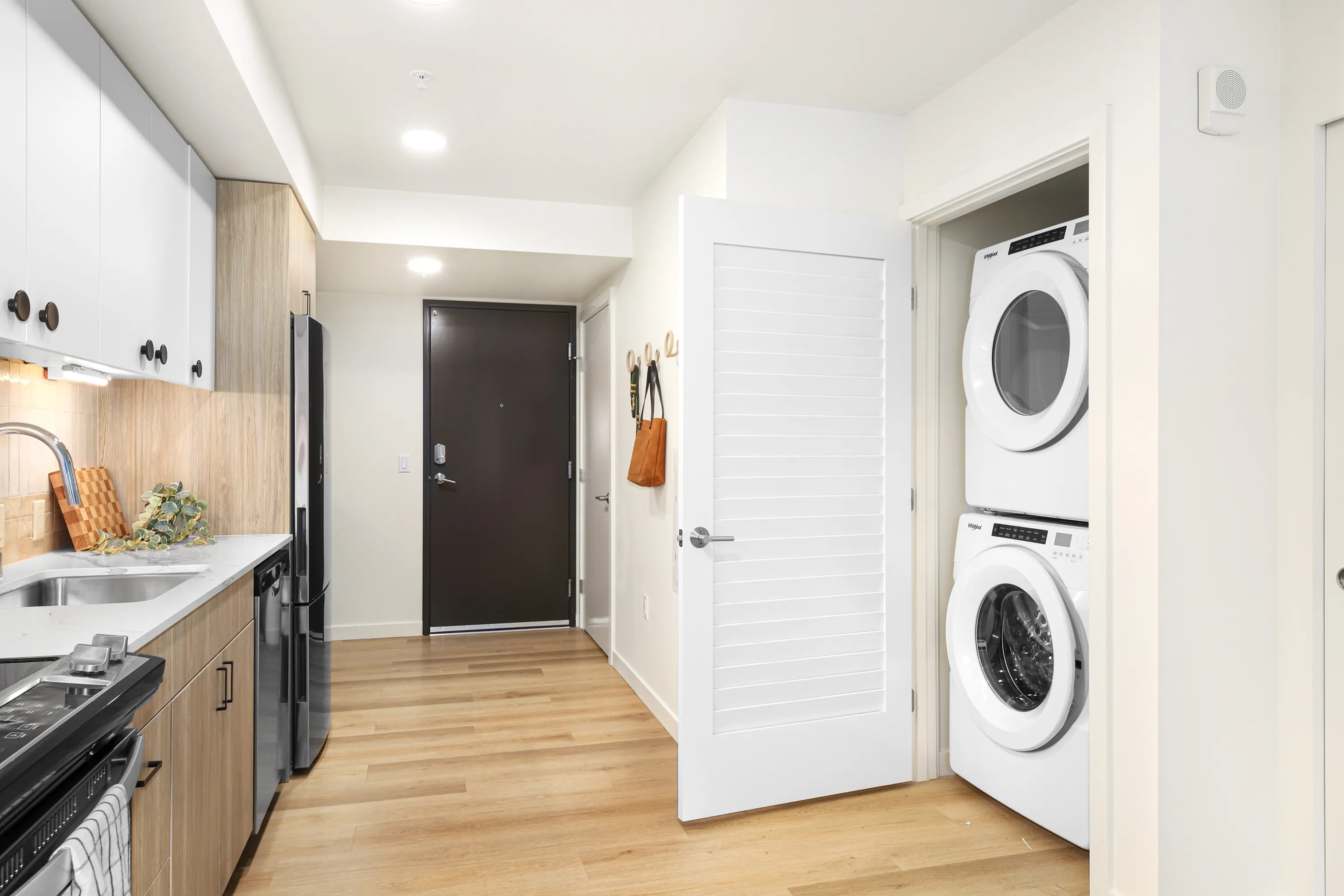 Chic modern kitchen with stainless steel appliances, stylish wooden cabinets, and cozy in-unit laundry area.