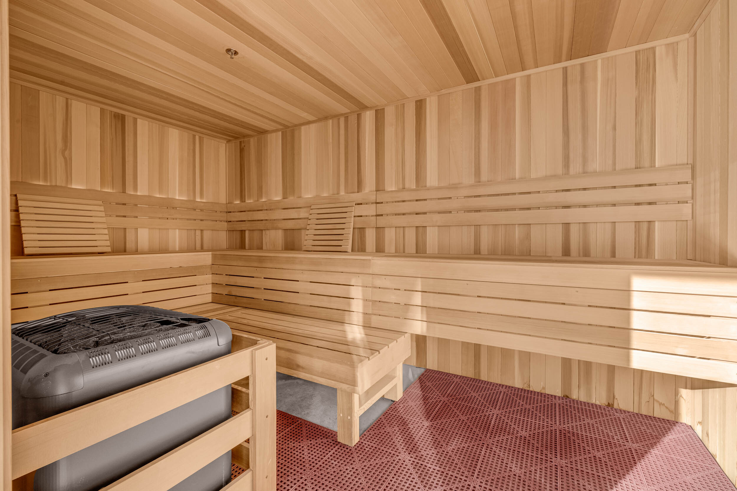 Luxurious wooden sauna with stylish benches and modern heating unit, offering a serene retreat.