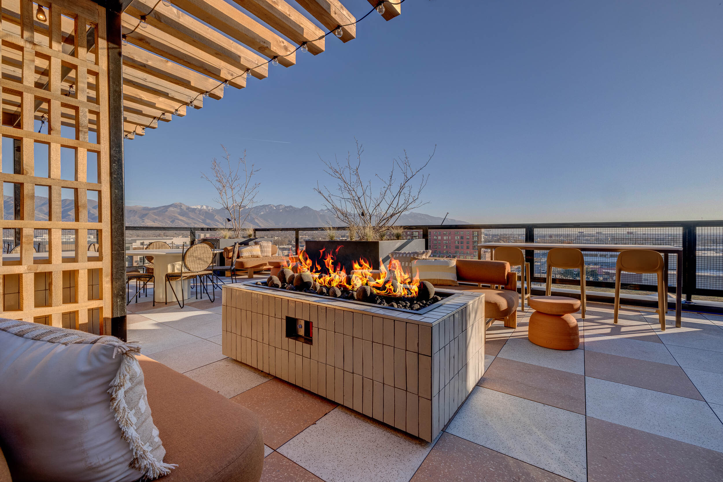 Chic rooftop terrace with cozy seating and a modern fire pit offering stunning mountain views.