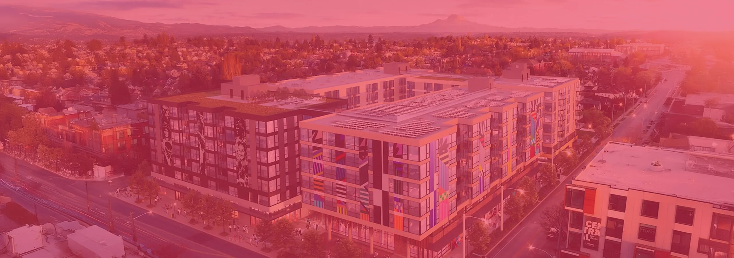 Vibrant urban apartment complex with colorful modern facade, offering rooftop green spaces in a lively neighborhood setting.