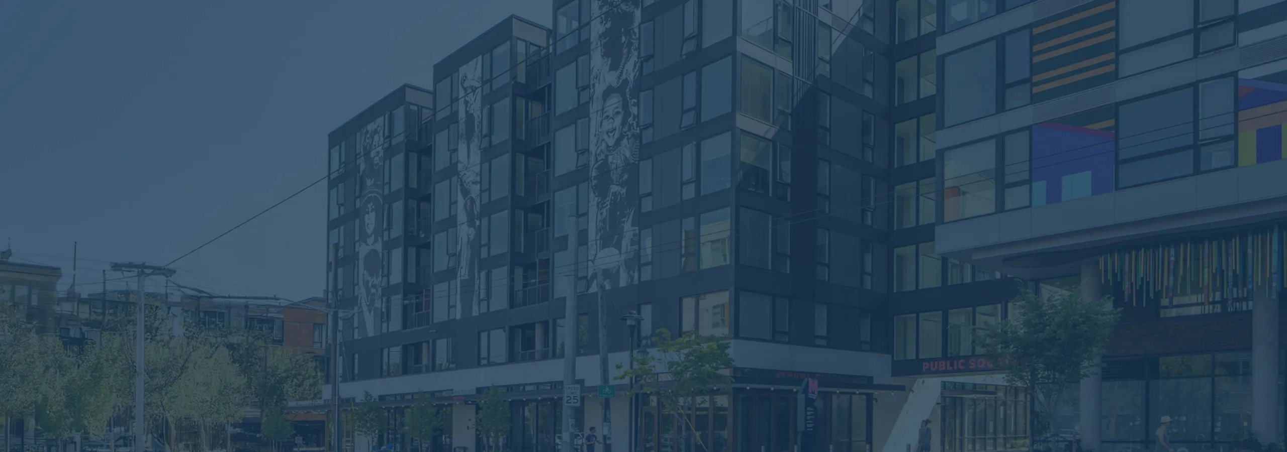 Modern urban apartment building with artistic murals and vibrant windows, located in a lively neighborhood.