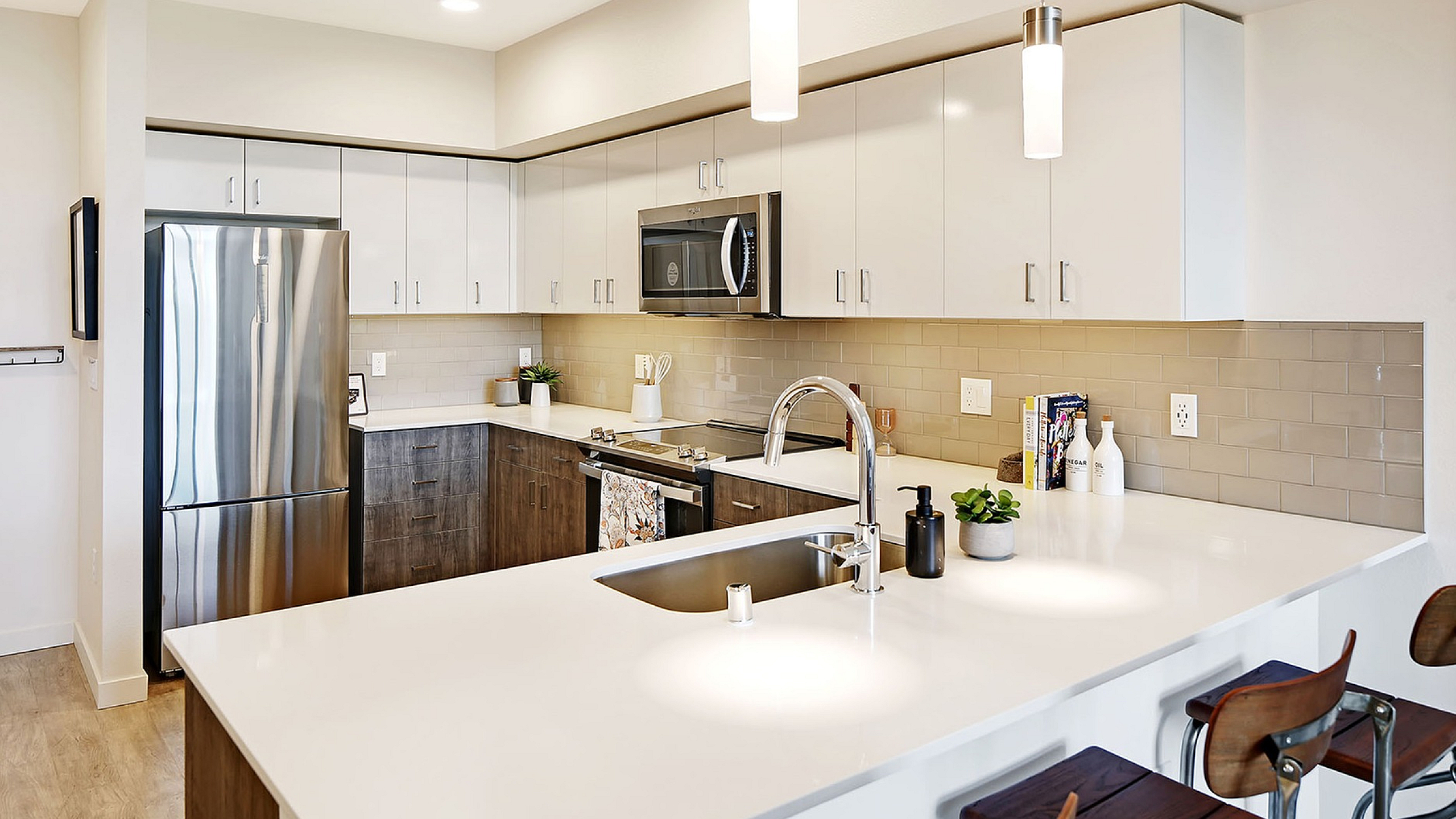 Modern kitchen with sleek stainless steel appliances, white cabinetry, and elegant pendant lighting, featuring a spacious countertop and stylish bar seating.