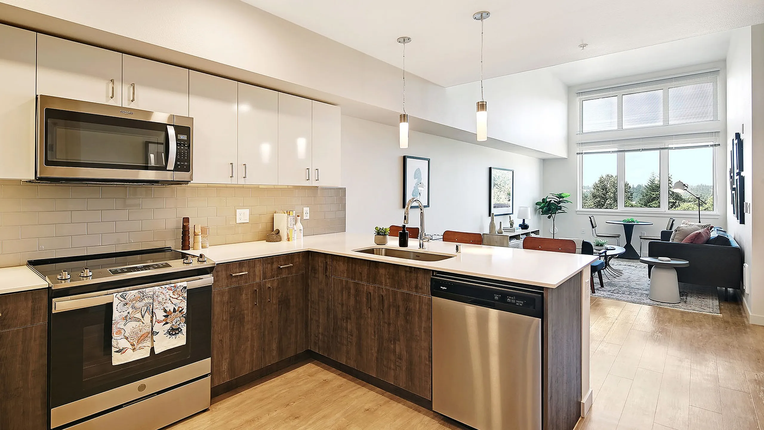 Modern open-concept kitchen with sleek stainless steel appliances, overlooking a bright living area with large windows and stylish decor.