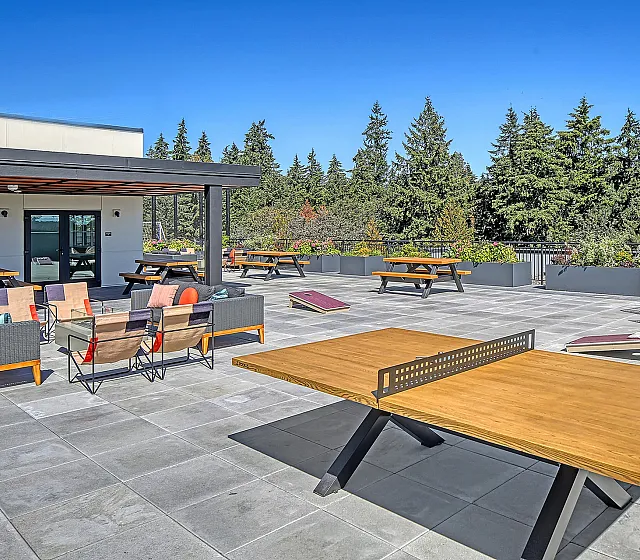 Chic rooftop terrace with modern seating, table tennis, and lush greenery, offering a perfect space for relaxation and entertainment.