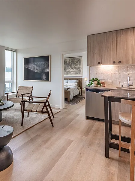 Bright and modern open-concept apartment featuring sleek kitchen, cozy living area with large windows, and elegant decor, ideal for urban living.