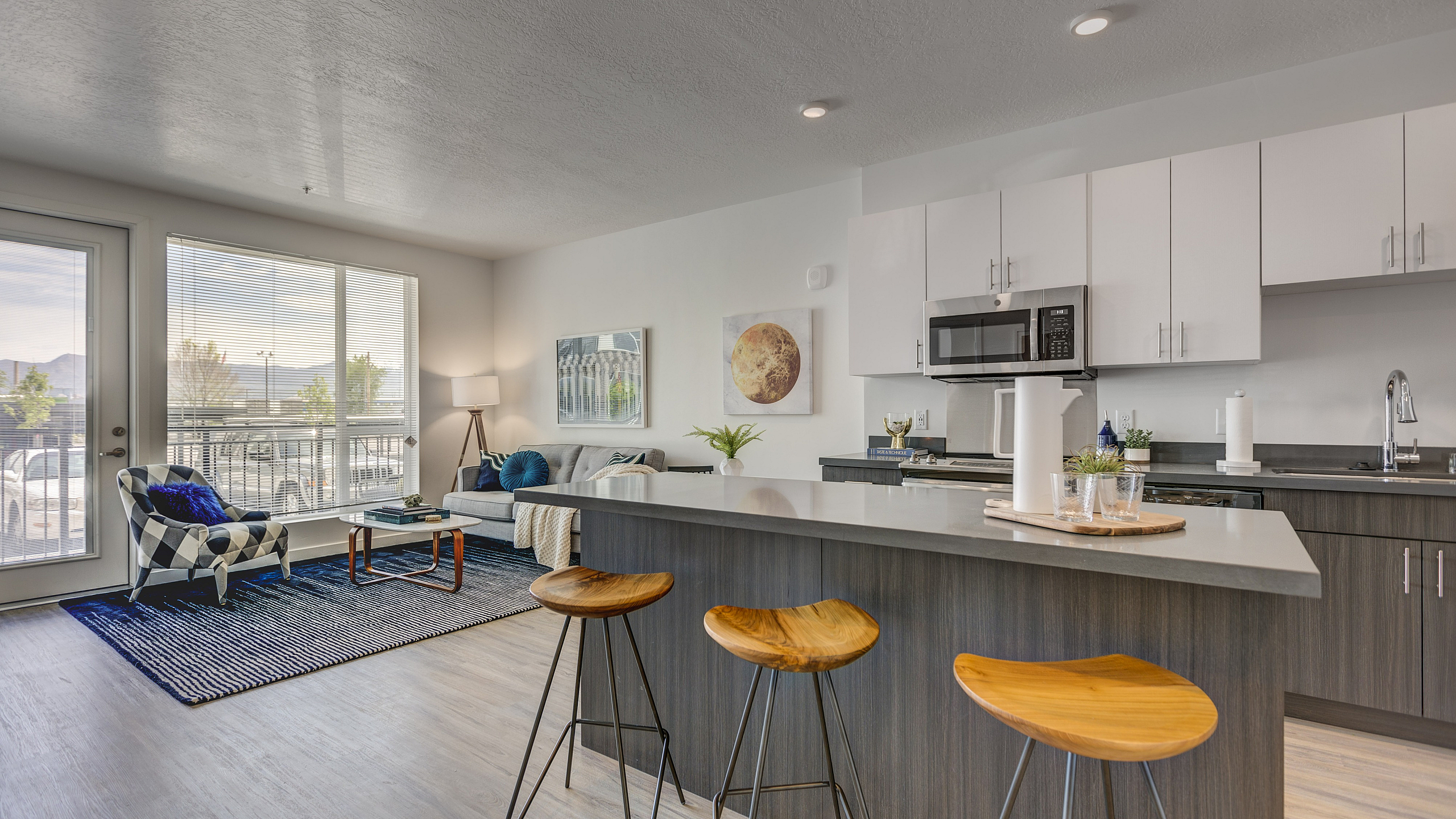 Bright and modern open-concept townhome living area featuring a sleek kitchen with a large island, stylish bar stools, and inviting living space with contemporary decor.