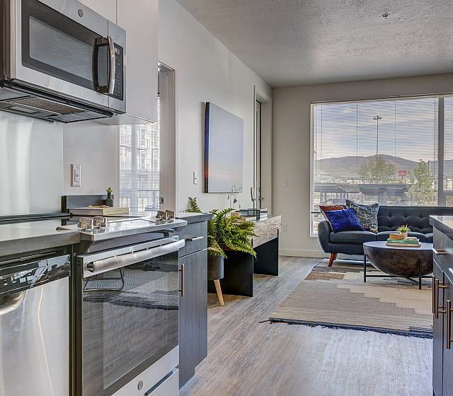 Modern open-concept kitchen and living area with sleek appliances, stylish decor, and large windows offering scenic views.