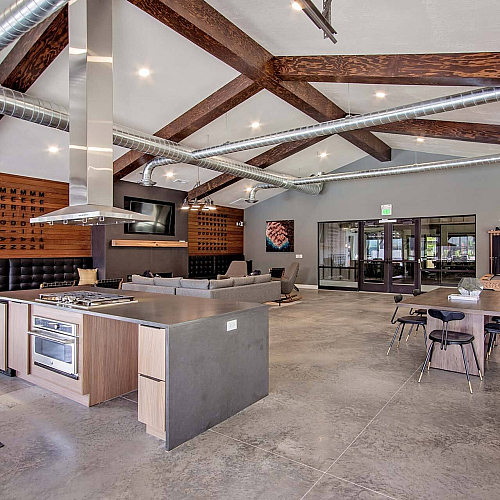 Modern open-concept living space with exposed beams and industrial ductwork, featuring a sleek kitchen, cozy seating area, and an inviting dining space.