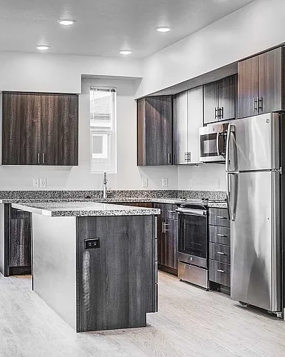 Modern kitchen showcasing sleek dark cabinets, stainless steel appliances, and ample natural light.