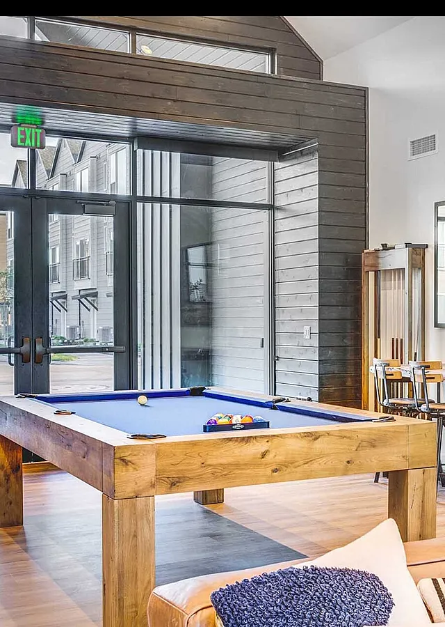 Inviting recreational space featuring a sleek pool table, modern high-top seating, and stylish decor with natural light.