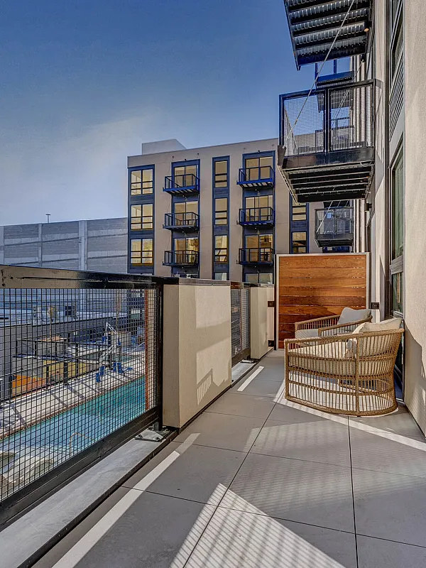 Chic urban balcony view featuring cozy seating, modern architecture, and a vibrant cityscape backdrop.