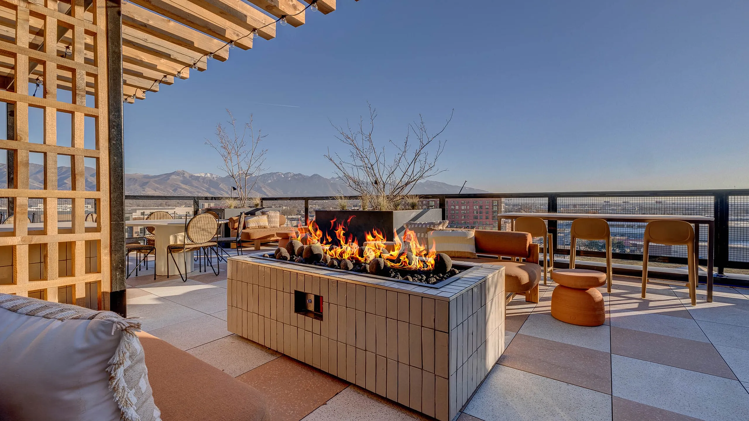 Chic rooftop terrace with modern fireplace, cozy seating, and stunning mountain views, offering a serene urban escape.