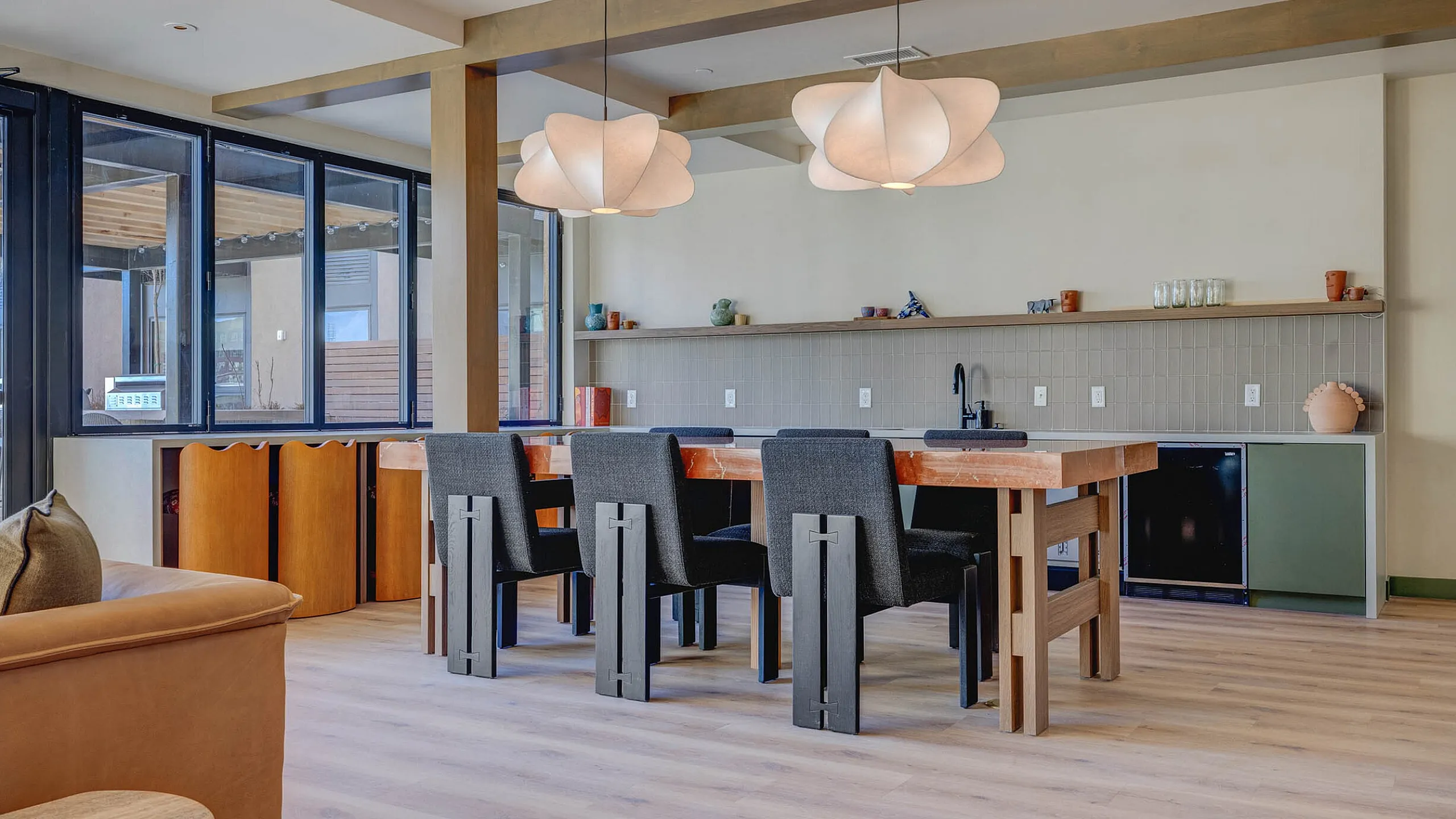 Modern open-concept dining area with stylish wooden table, sleek black chairs, and artistic pendant lights in a bright, inviting space.