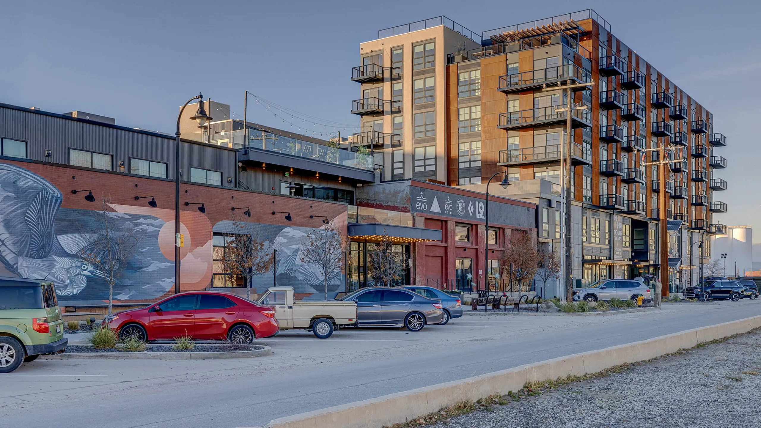 Chic urban apartment complex with vibrant exterior murals and modern architectural design, featuring spacious balconies and a lively street view.