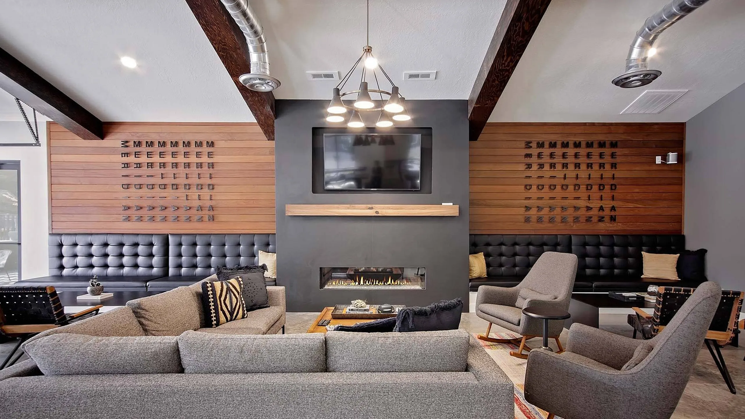 Contemporary lounge area with stylish gray furniture, modern fireplace, and wooden accent walls, creating an inviting atmosphere.
