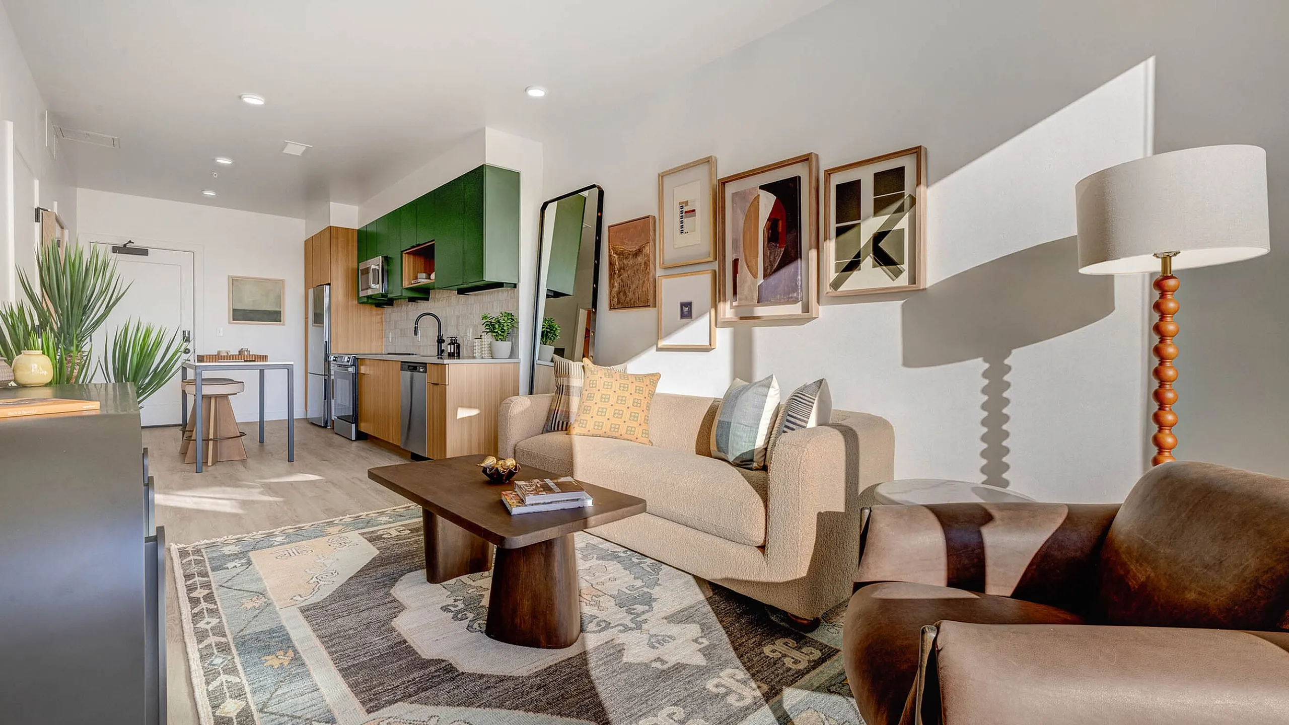Elegant modern living room with stylish decor, featuring a cozy beige sofa, vibrant green kitchen cabinets, and warm natural lighting.