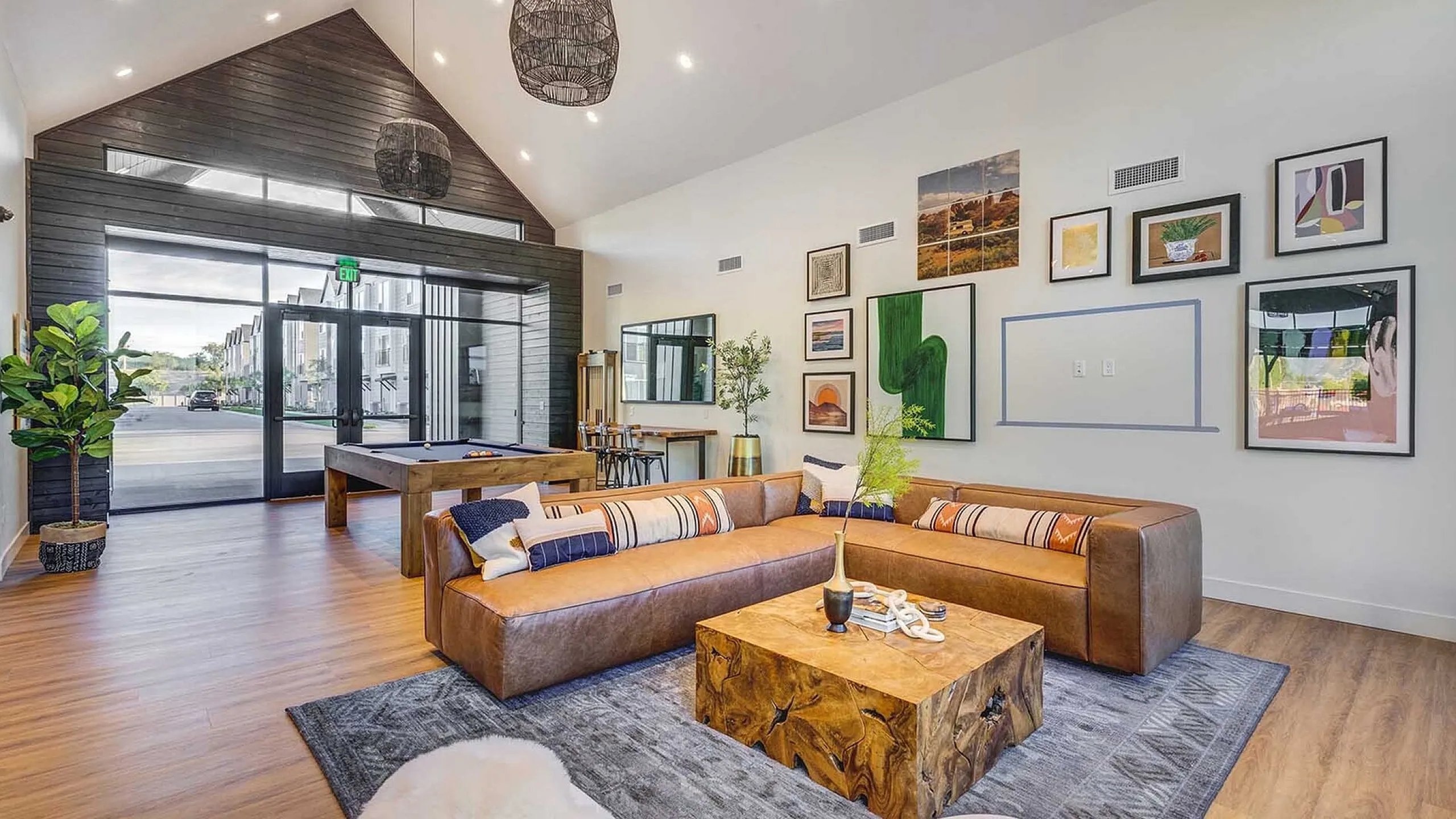 Bright and inviting living room with high ceilings, modern decor, and cozy seating, featuring a pool table and wall art for a stylish urban retreat.