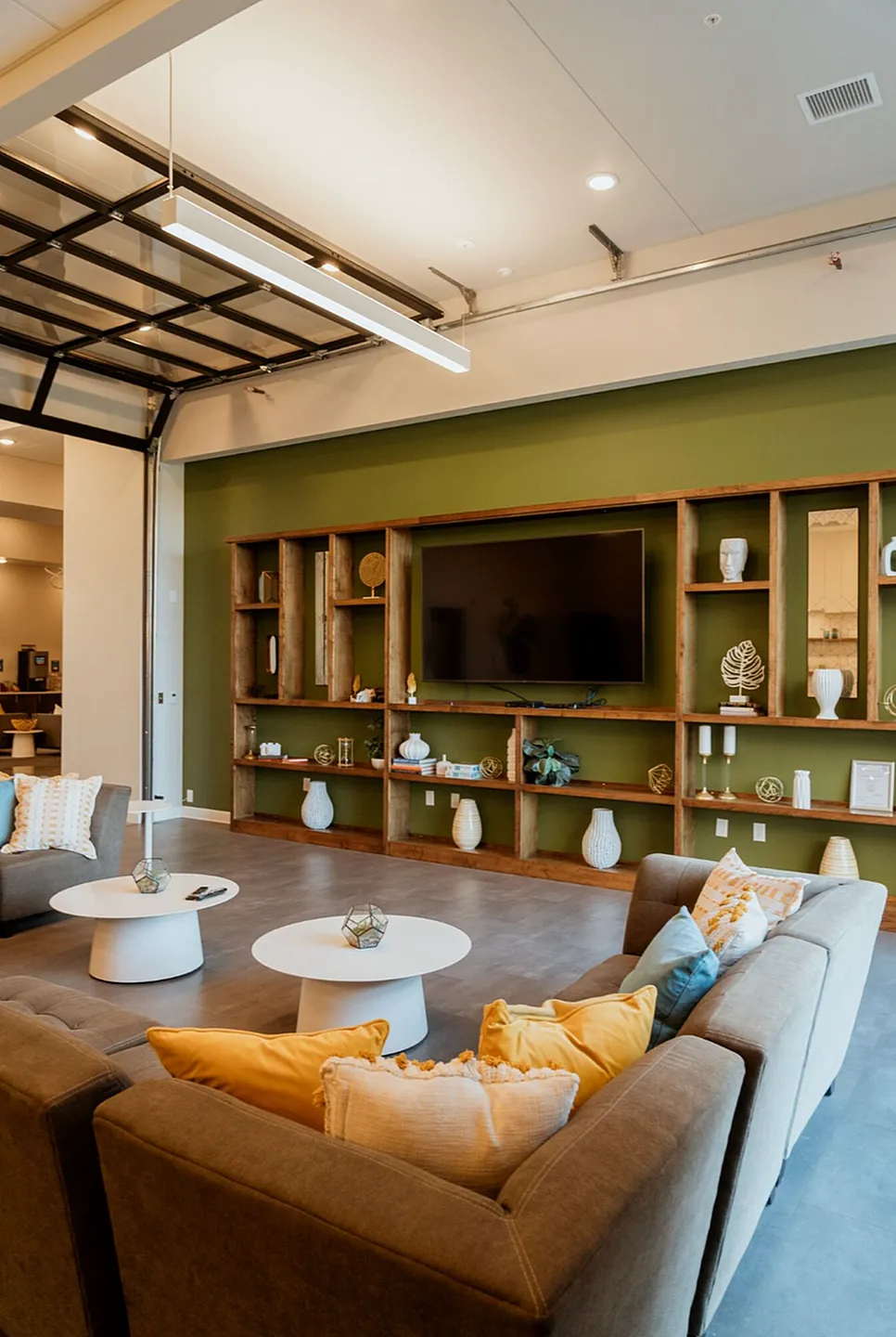 Contemporary living room with chic decor, featuring a large TV, stylish open shelving, and a cozy sofa adorned with colorful pillows.
