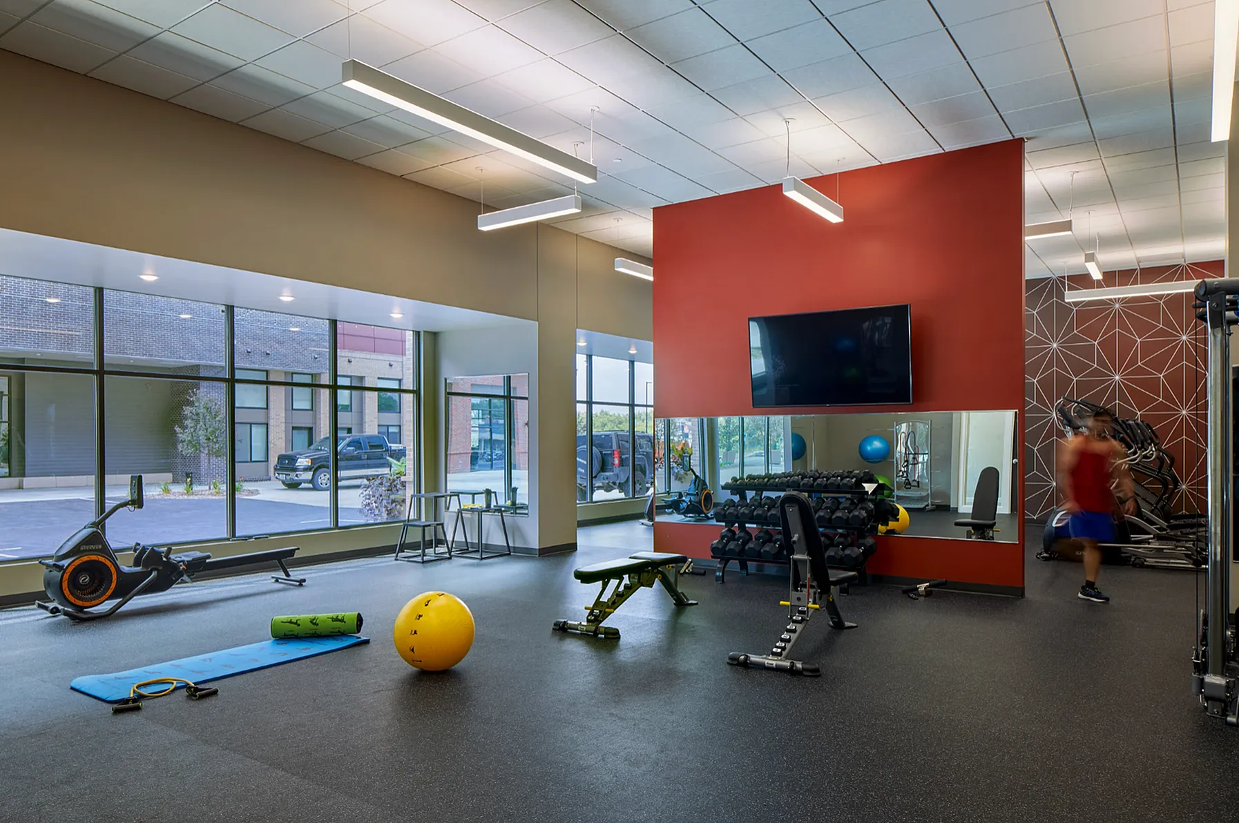 Modern fitness center featuring state-of-the-art equipment, vibrant decor, and large windows offering natural light.