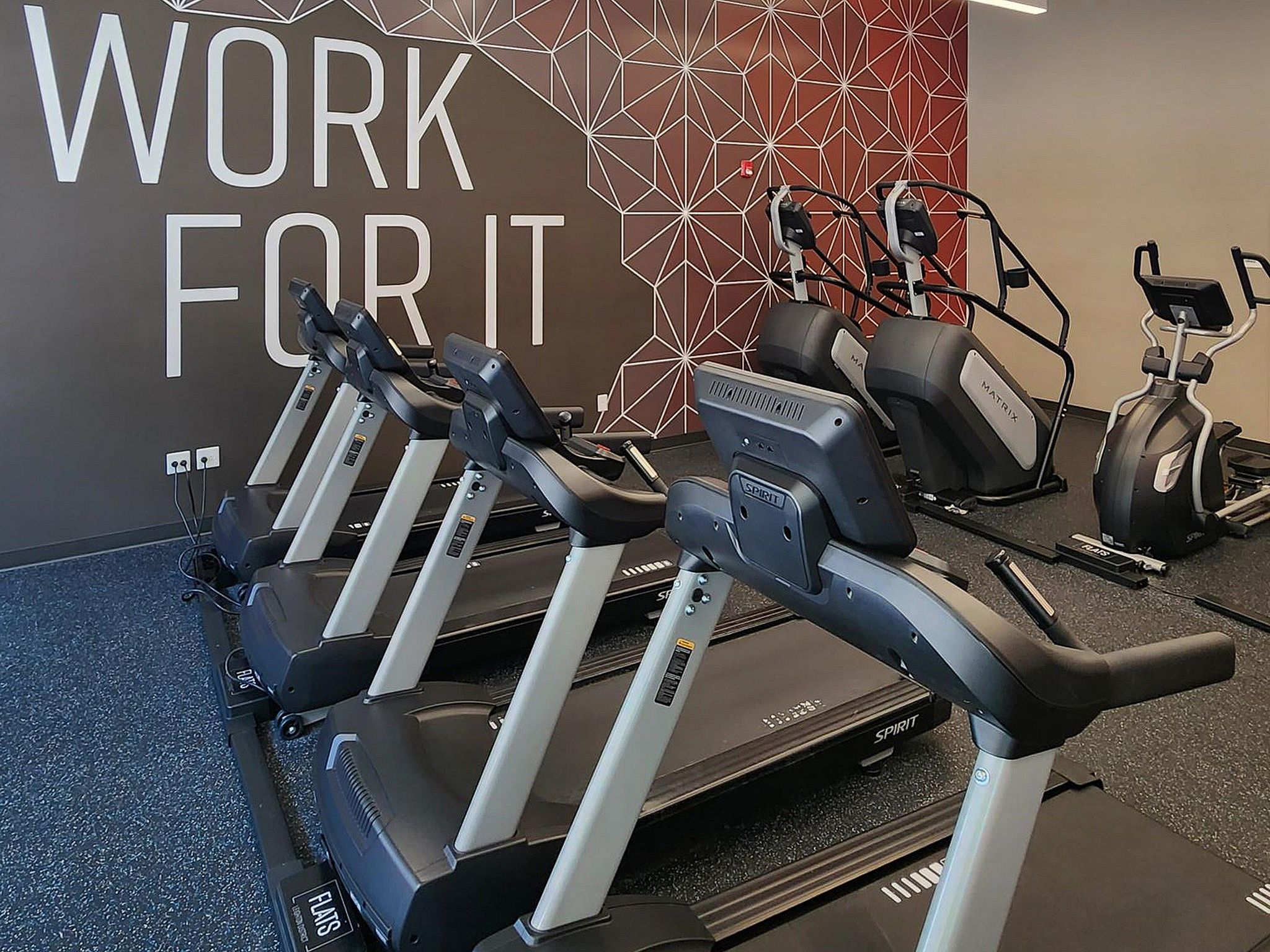 Modern fitness center with motivational wall art and state-of-the-art exercise equipment, including treadmills and ellipticals.