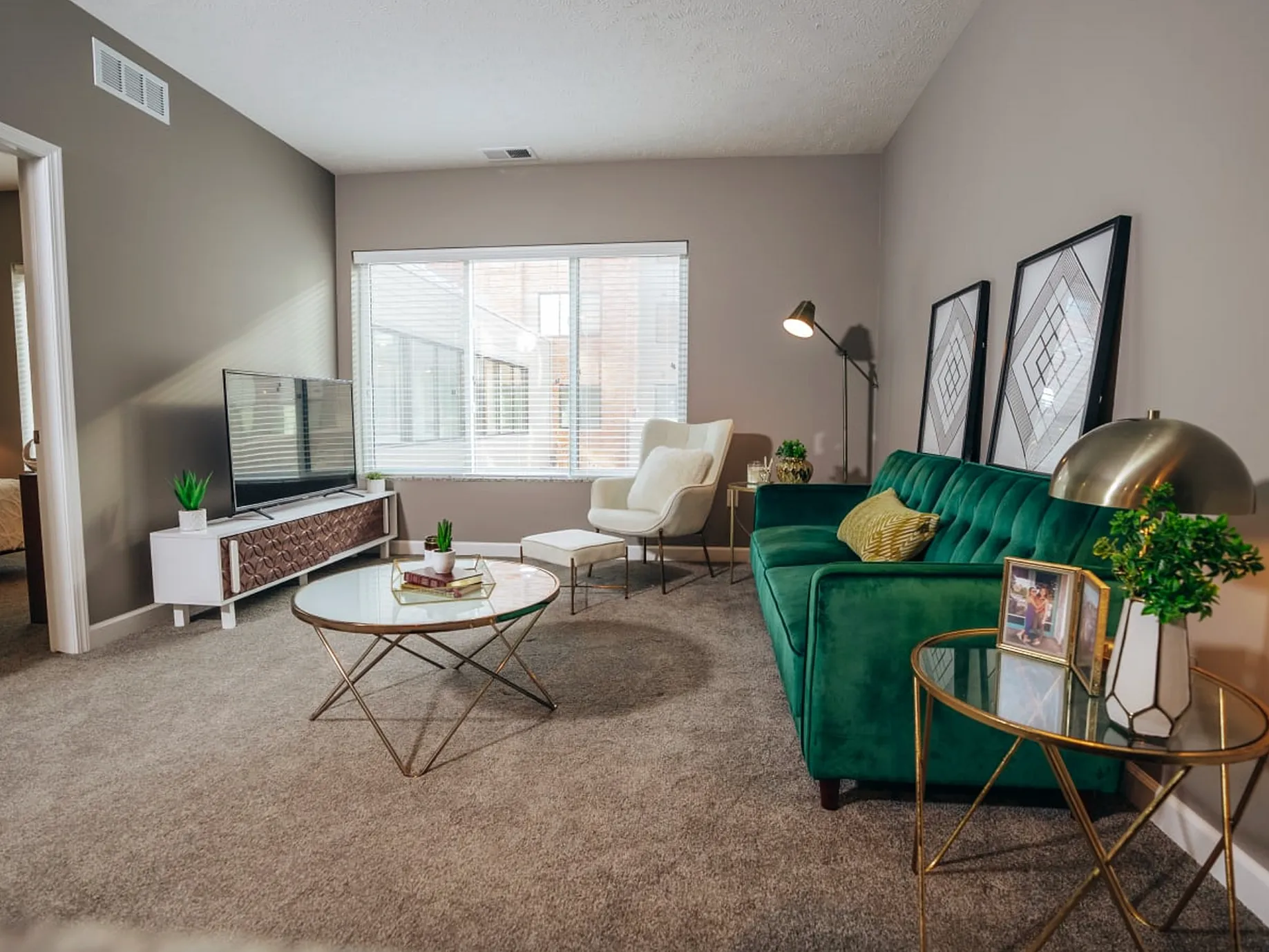 Elegant living room with a plush green sofa, modern decor, large window with natural light, and stylish furnishings.