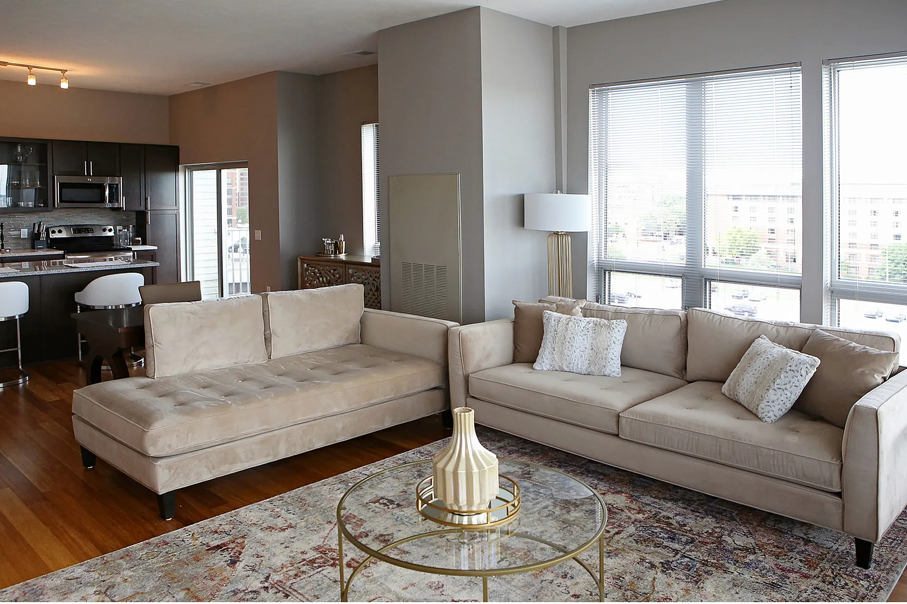 Chic open-concept living space with modern kitchen, plush seating, and panoramic city views through large windows.