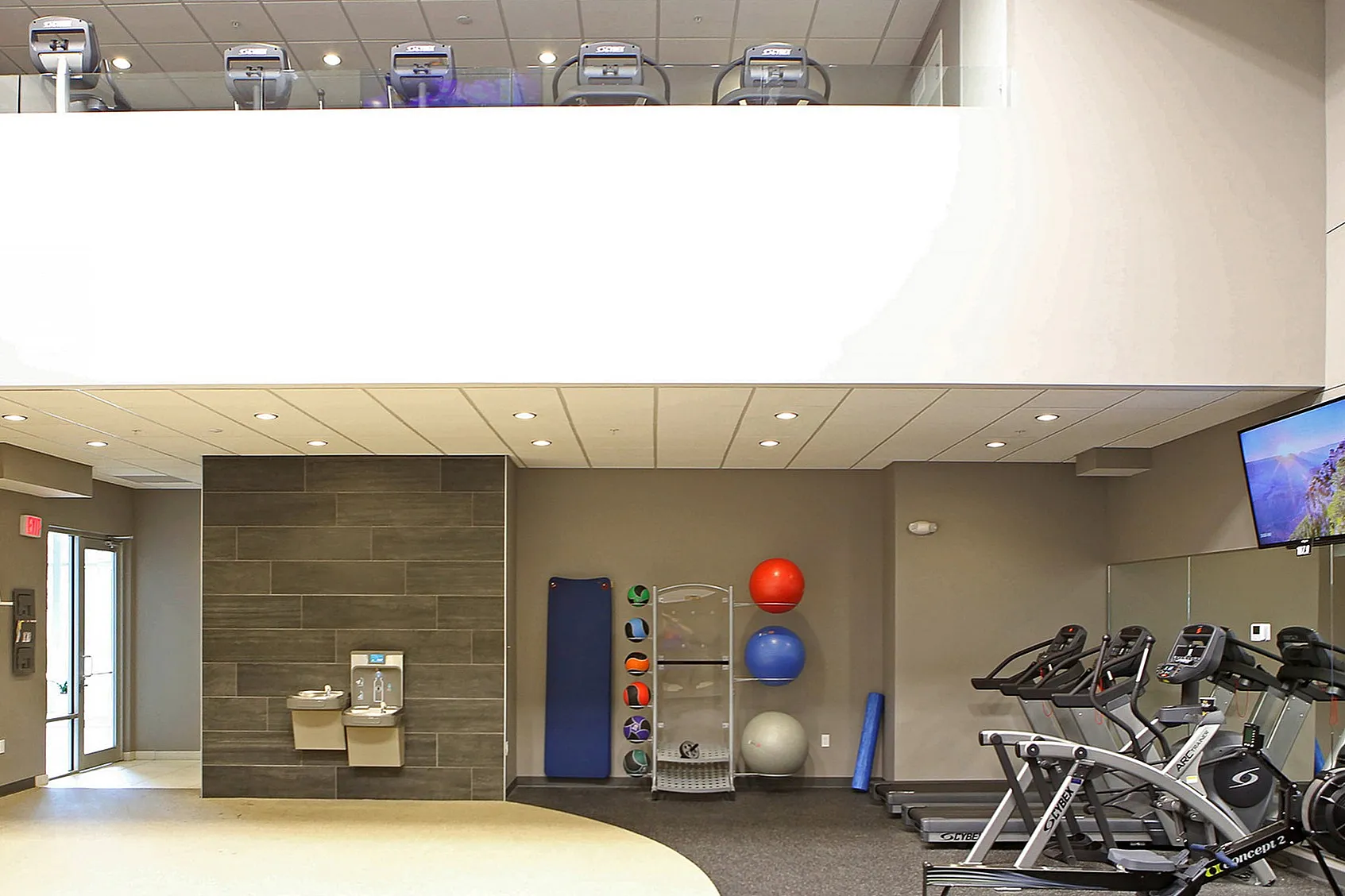 Modern fitness center featuring state-of-the-art treadmills, exercise balls, and a sleek hydration station.