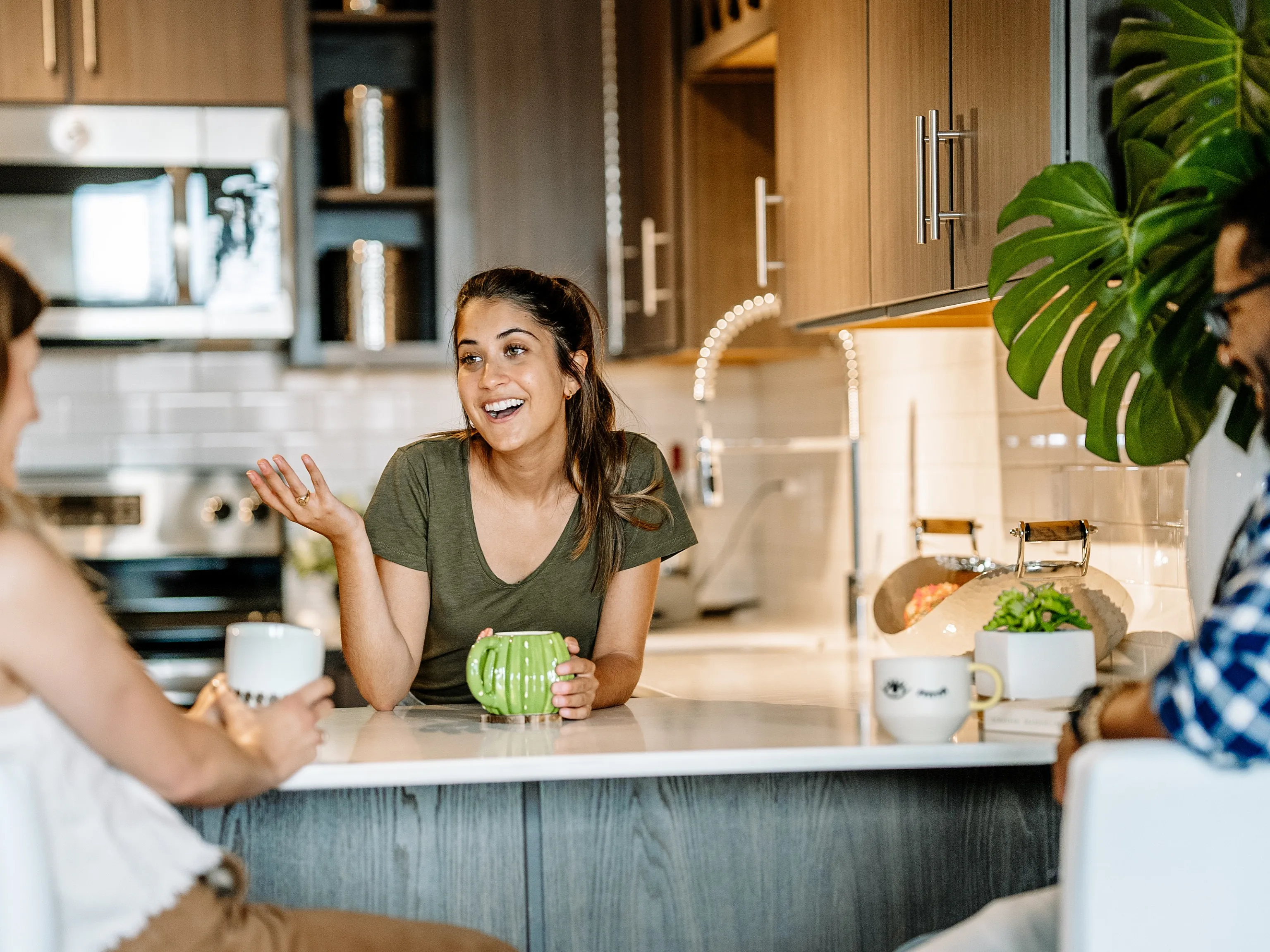Modern kitchen with sleek wooden cabinets, stainless steel appliances, and a cozy breakfast bar where friends enjoy a lively chat.