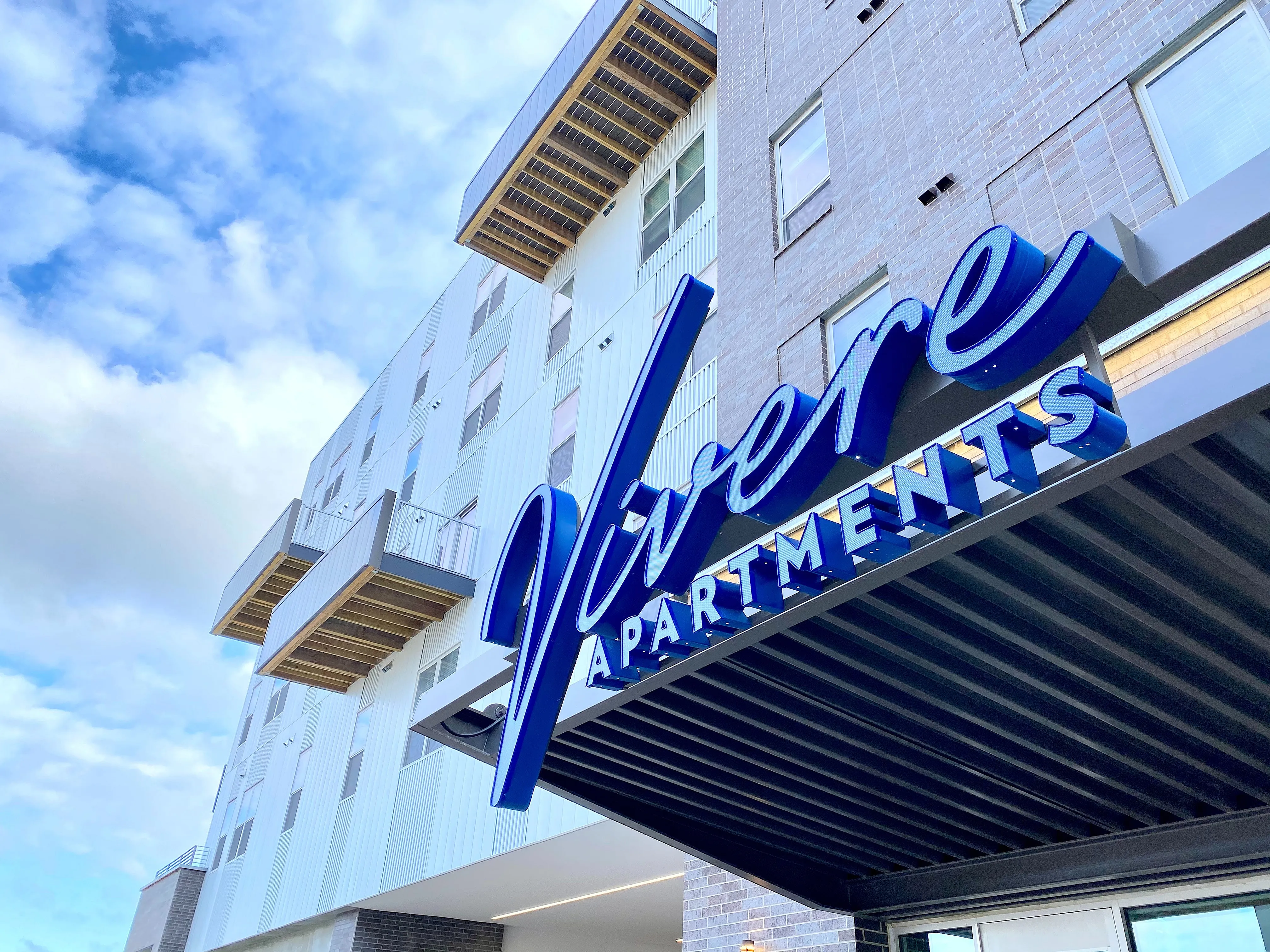 Modern Vivere Apartments exterior showcasing elegant balconies and sleek architecture under a vibrant sky.