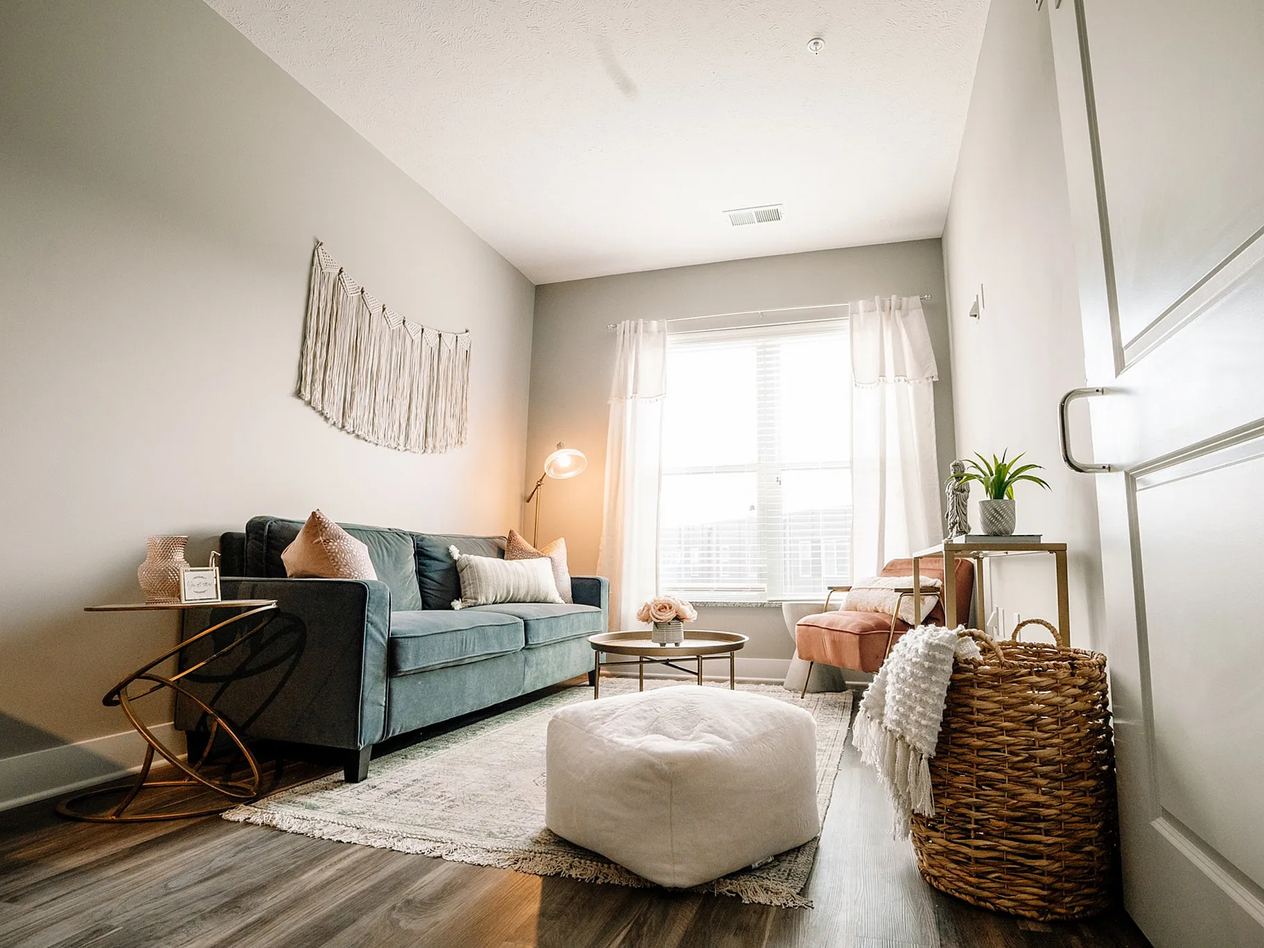 Cozy and stylish living room with a teal sofa, elegant decor, natural light, and hardwood flooring.