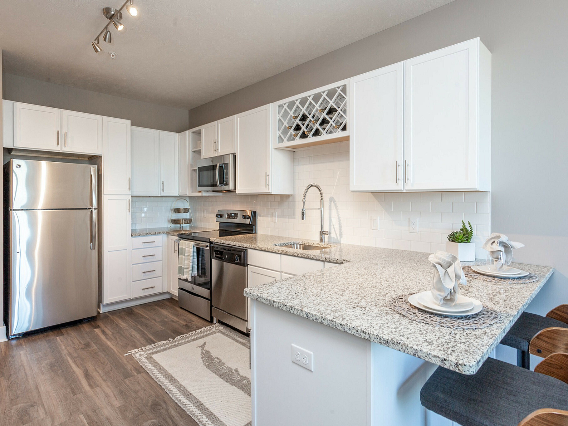 Modern kitchen with sleek stainless steel appliances, granite countertops, and chic white cabinets, perfect for culinary enthusiasts.