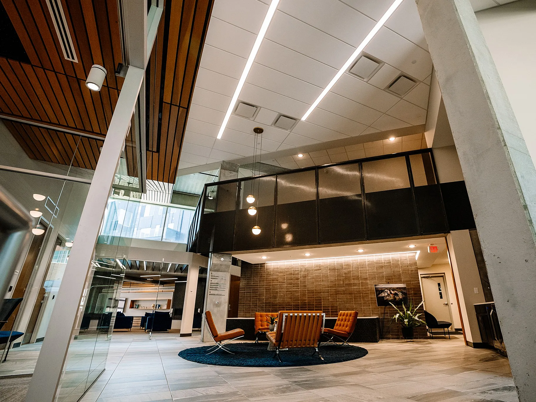 Modern lobby with elegant wood paneling, stylish orange chairs, and chic lighting creating a welcoming atmosphere.
