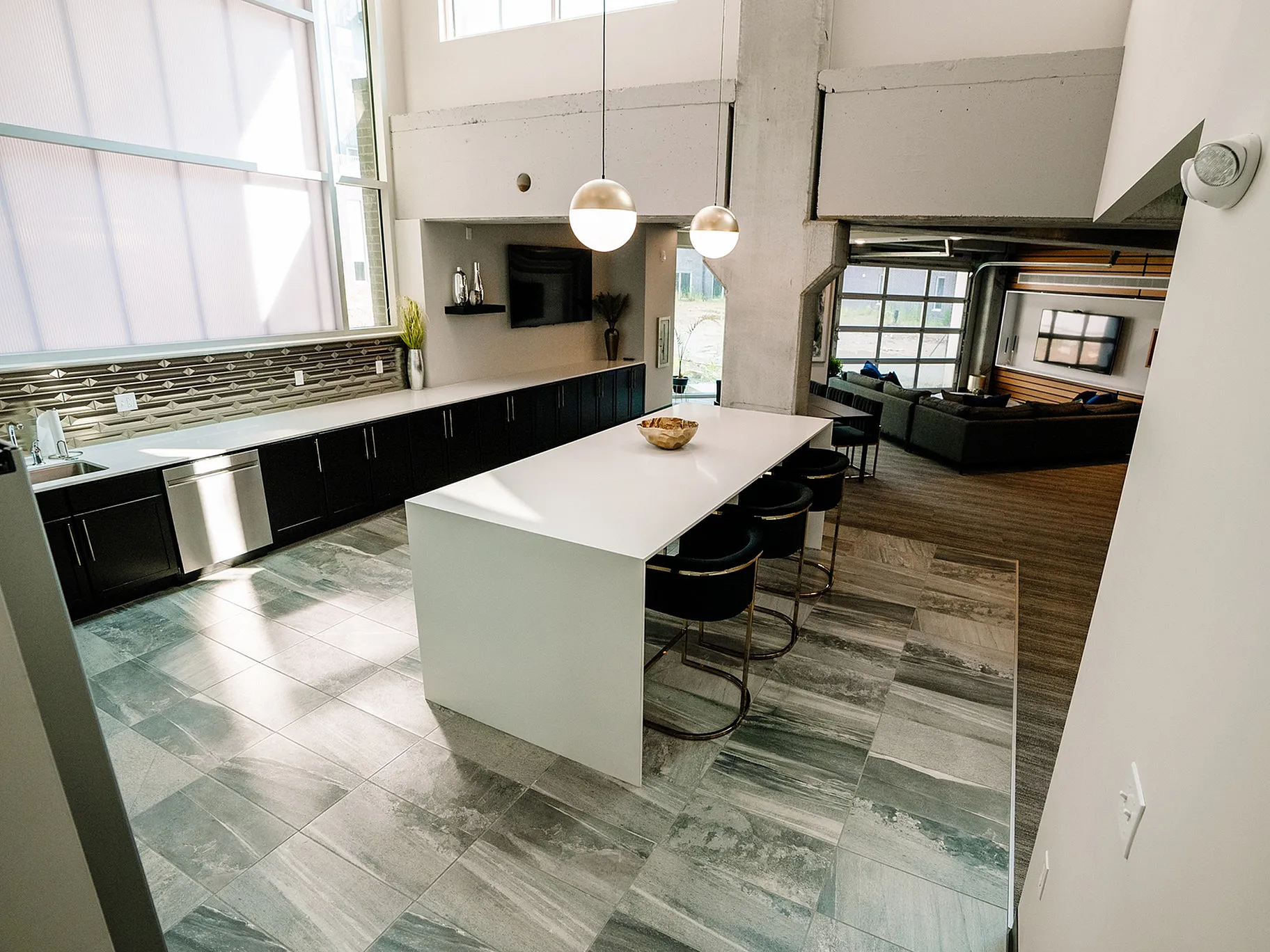 Luxurious modern kitchen featuring a sleek island with bar seating, high ceilings, and an elegant open-concept design flowing into a stylish living area.