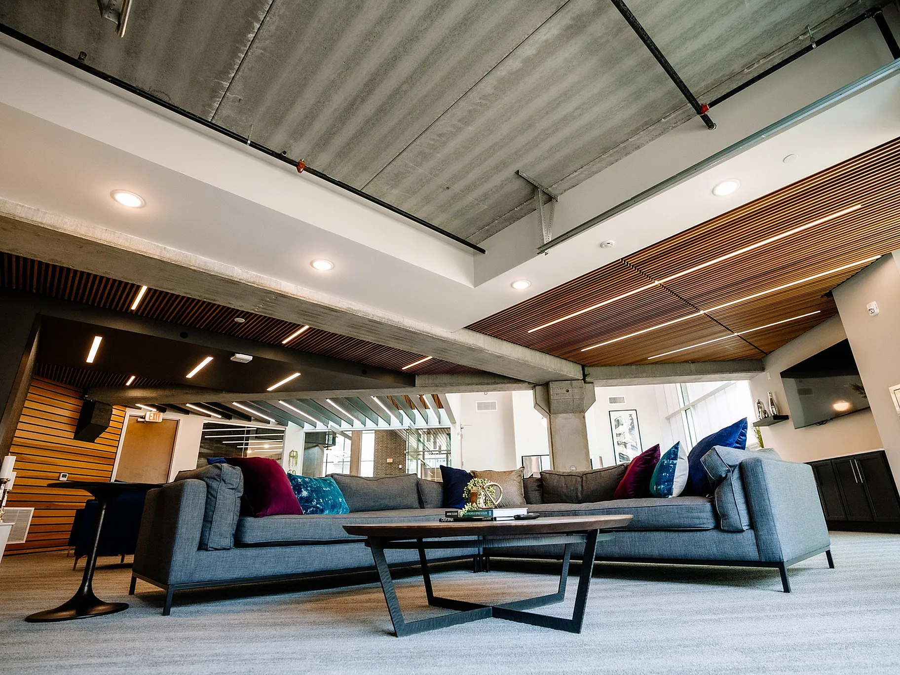 Sleek modern living room with contemporary furniture, stylish wood ceiling accents, and vibrant decor.