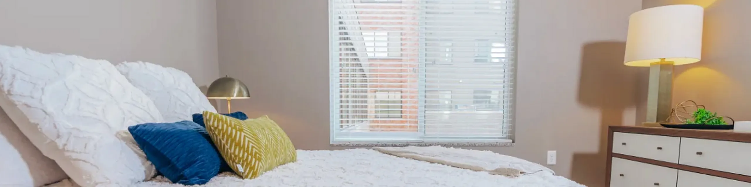 Inviting bedroom with cozy textured bedding, vibrant accent pillows, and warm lighting for a serene retreat.