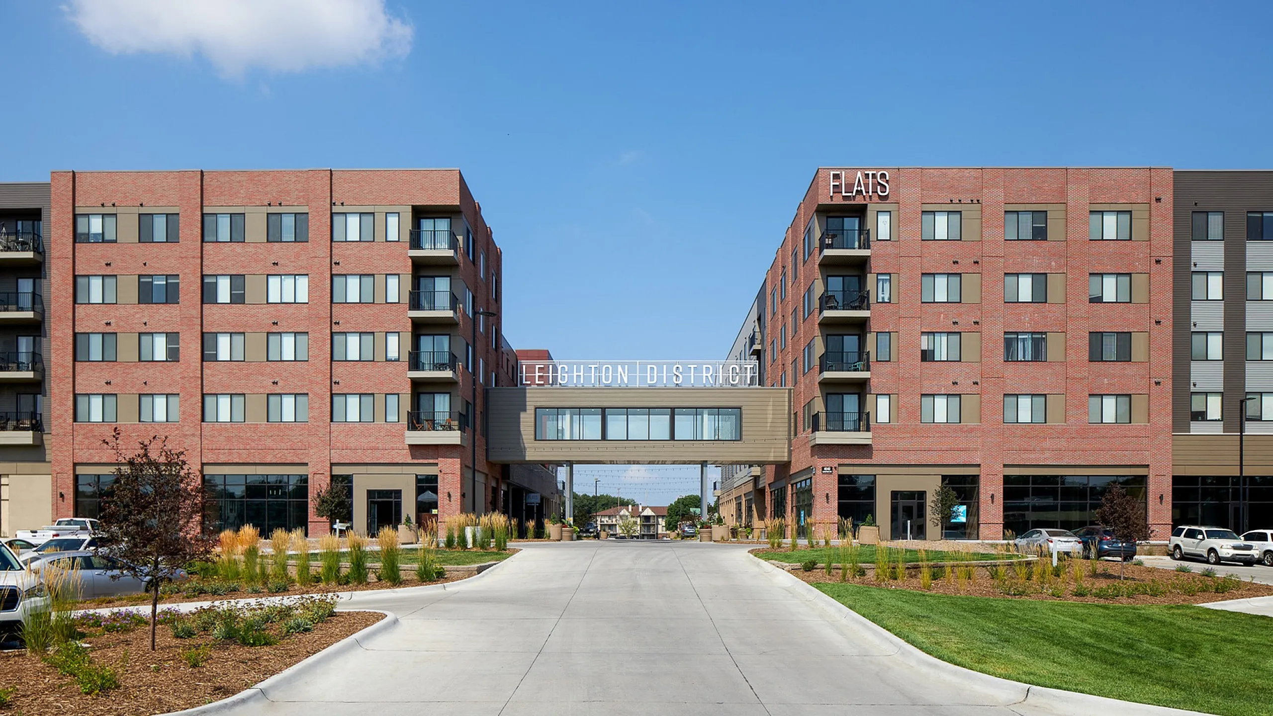 Modern apartment complex with urban design, featuring brick facade and a central walkway, named Leighton District.