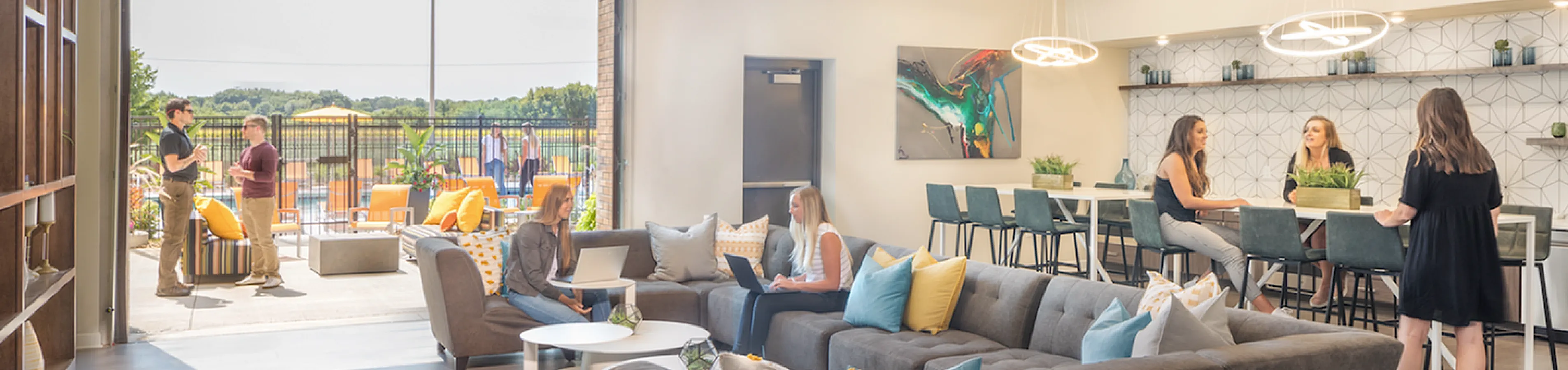 Modern communal lounge with cozy seating, bright natural light, and outdoor patio access, ideal for socializing and relaxation.