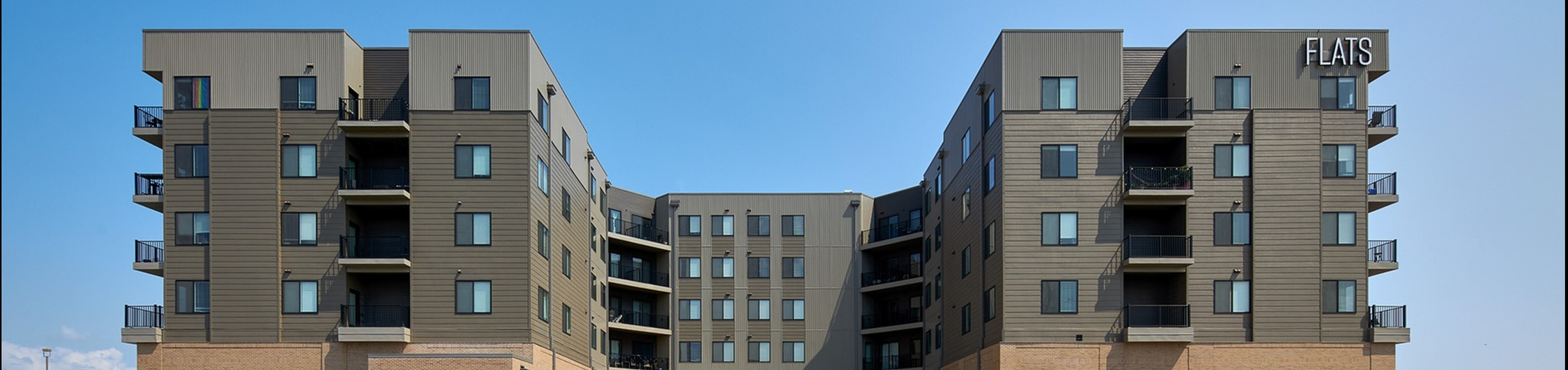 Modern residential building featuring sleek design with multiple balconies and contemporary finishes under a clear blue sky.