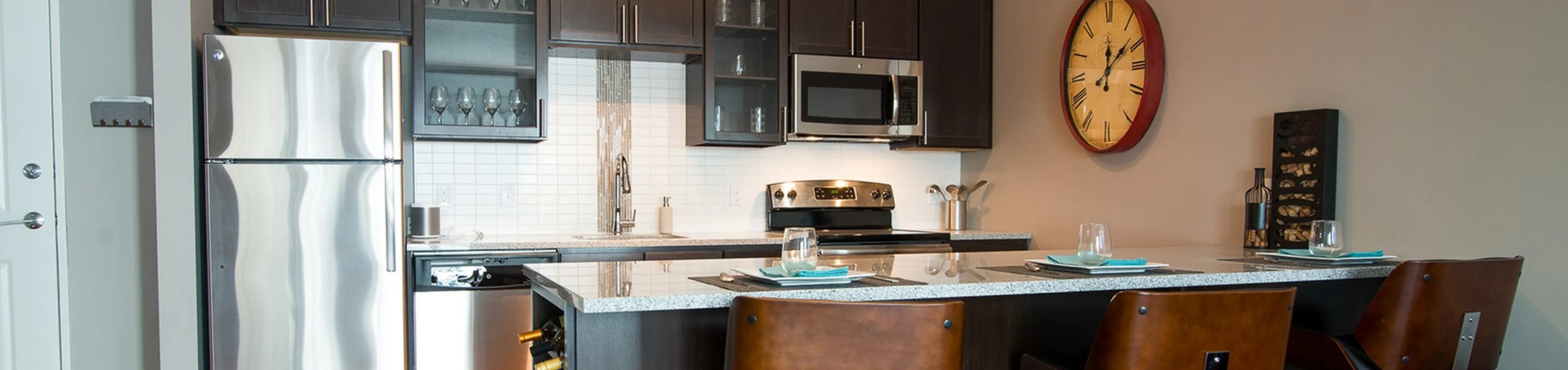 Modern kitchen with stainless steel appliances, sleek dark cabinetry, and stylish bar seating, exuding elegance and functionality.