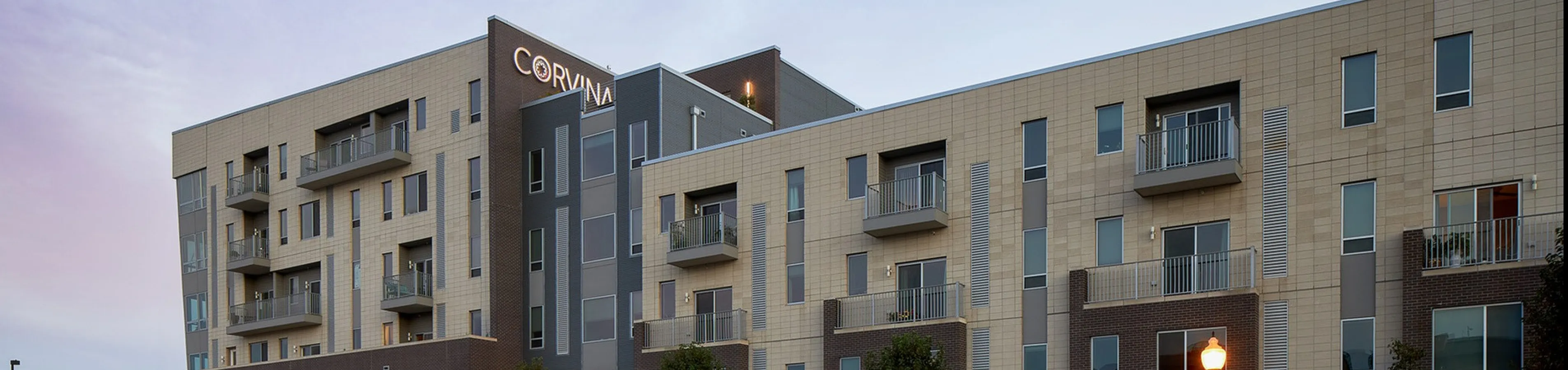 Modern apartment building exterior with sleek design, expansive windows, and individual balconies, capturing a vibrant urban lifestyle.