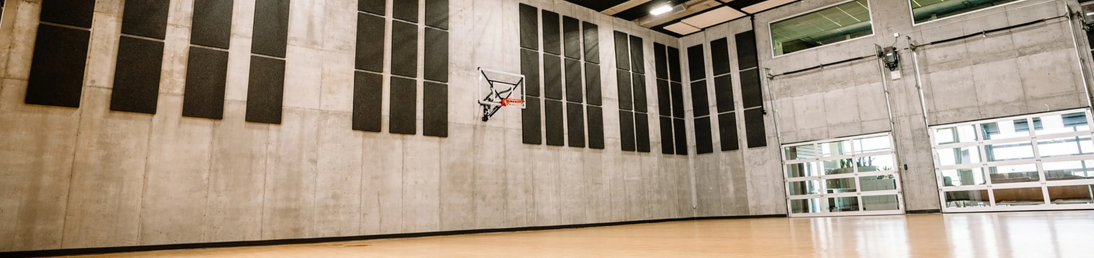 Spacious indoor basketball court with modern design, featuring sleek wooden flooring and acoustic paneling for an optimal playing experience.