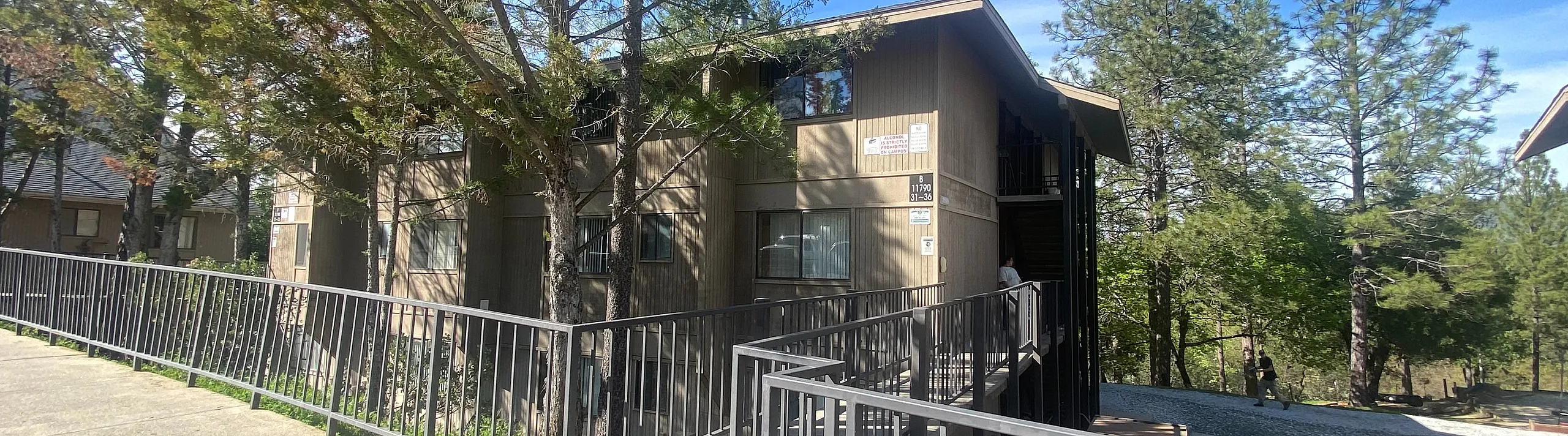 Charming apartment complex nestled in a serene wooded environment, surrounded by lush trees and offering tranquil living.